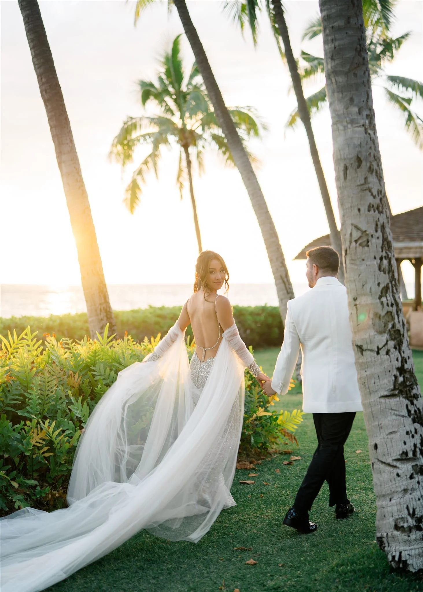 bride and groom walking sunset at Lanikuhonua