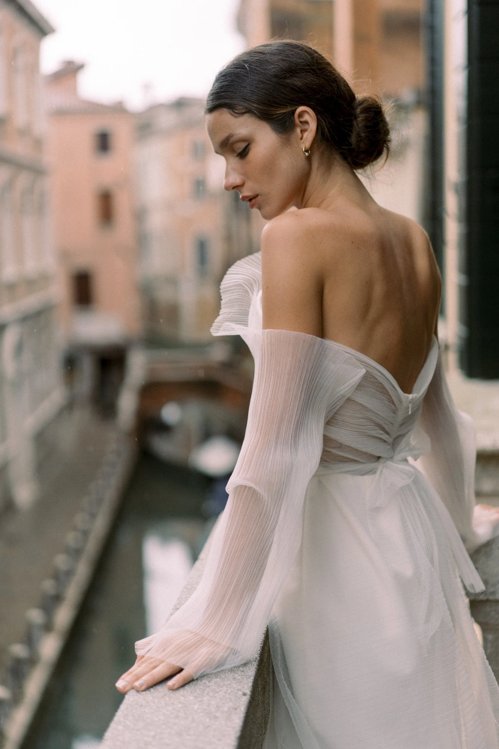 bride in couture gown looking over gondolas in Venice