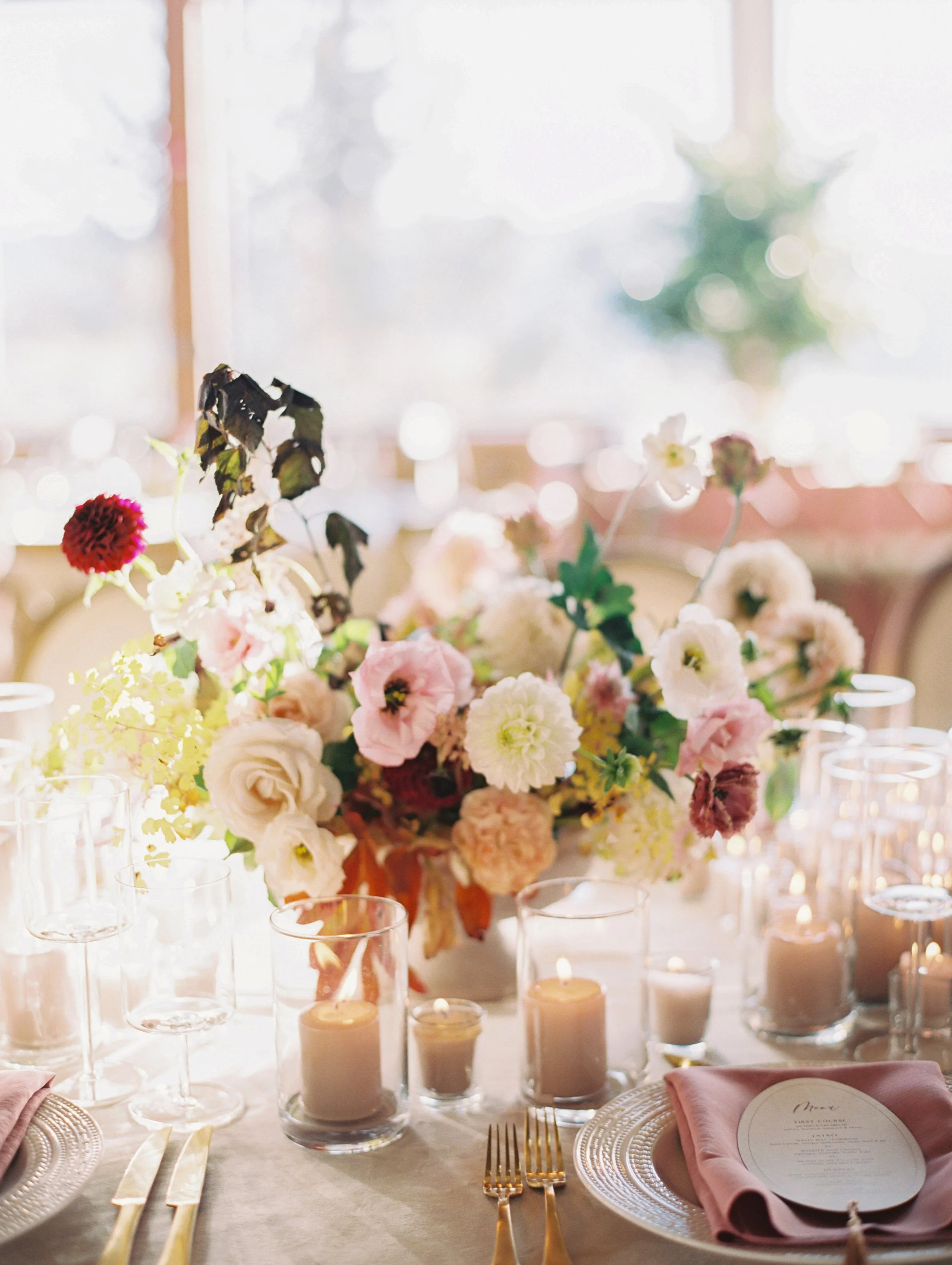 a flower arrangement in a vase with a ton of candles in front of it