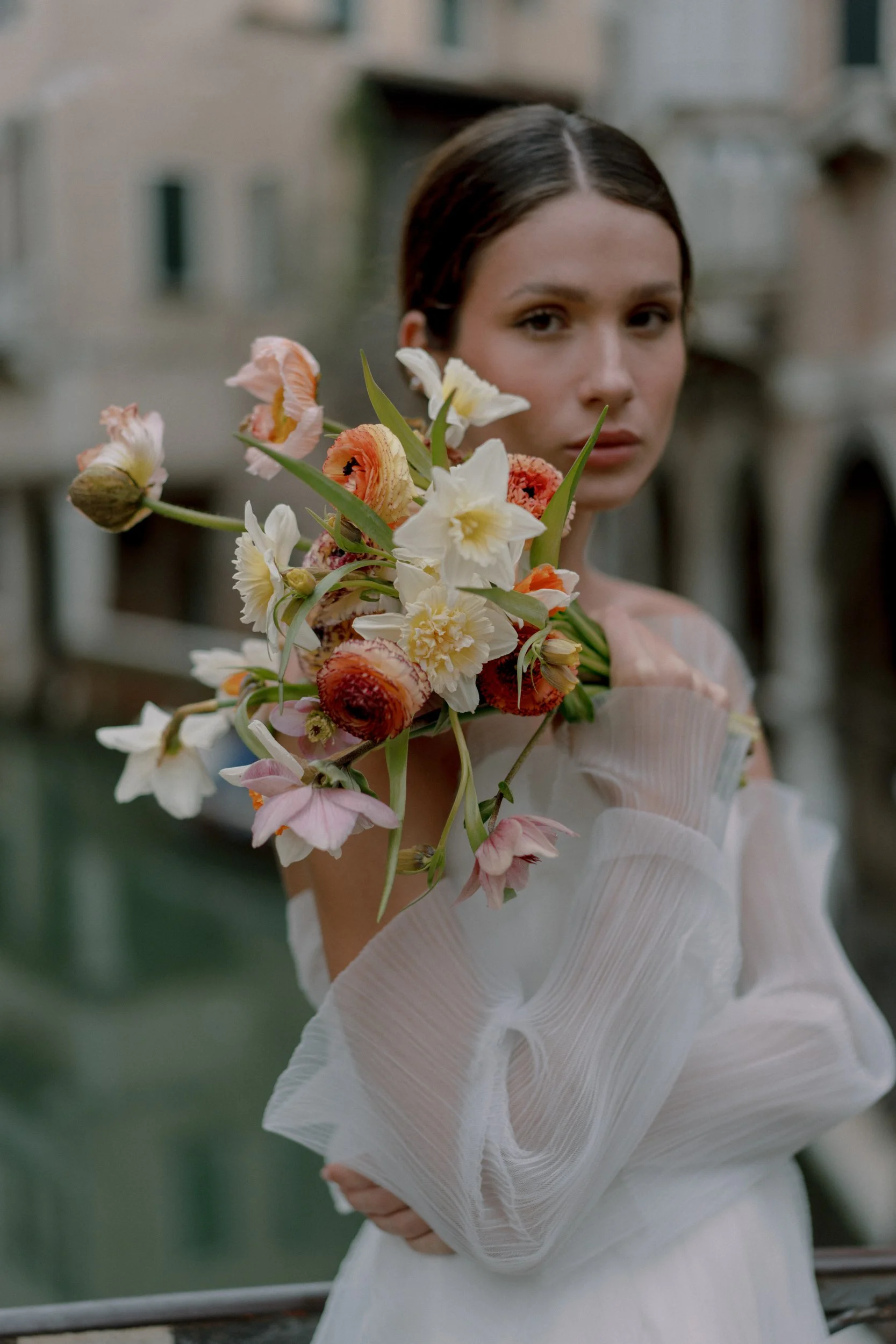 bride in Venice holding bouquet of poppies, daffodils, and ranunculus