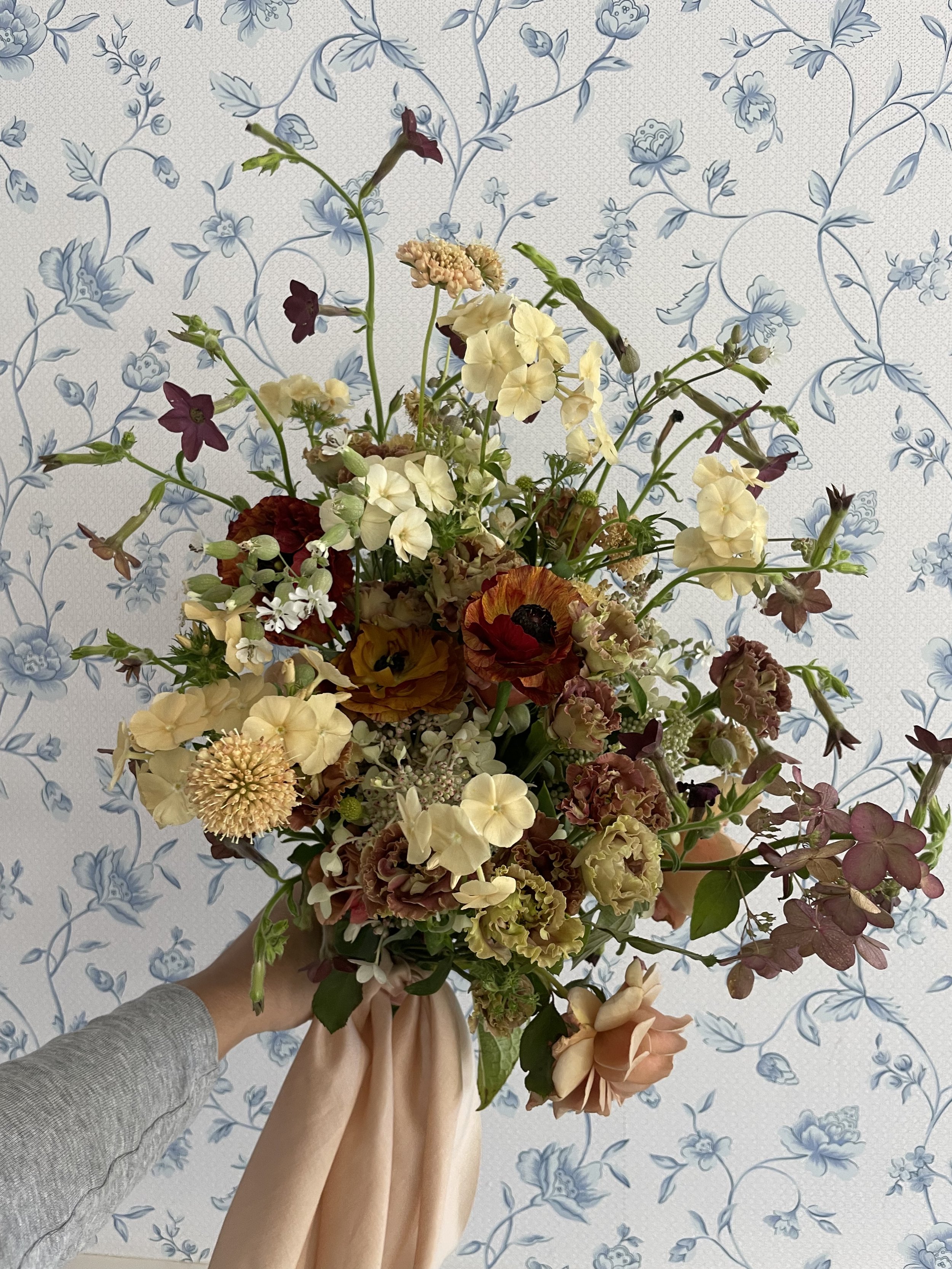 a small bouquet of flowers with nude, pale yellow, and rust -toned flowers