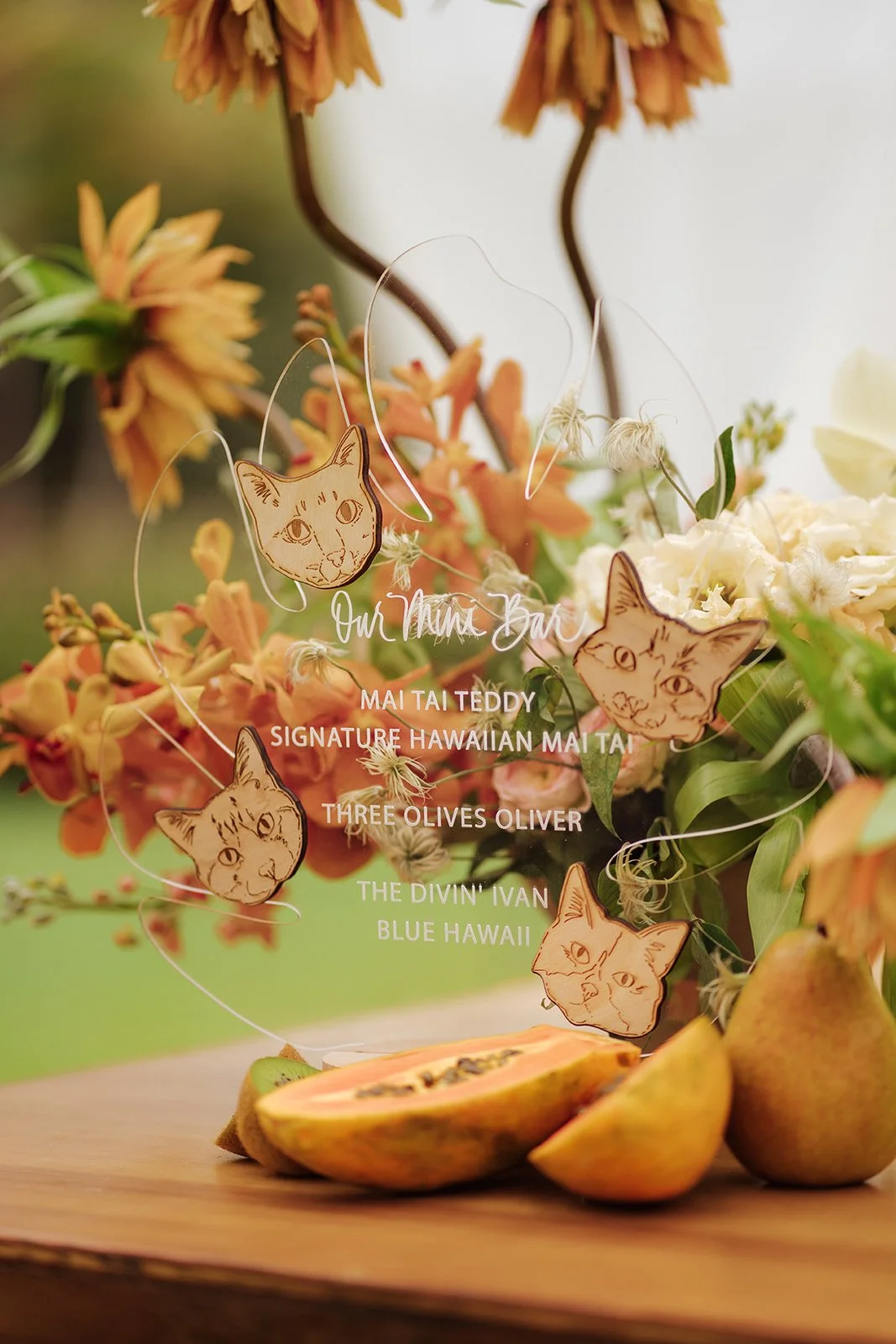 papayas sitting on wood table with cats on acrylic sign in front of orange flowers