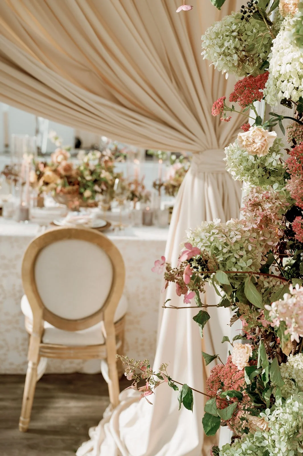 a chair with a cream draping with floral on one side and floral in background