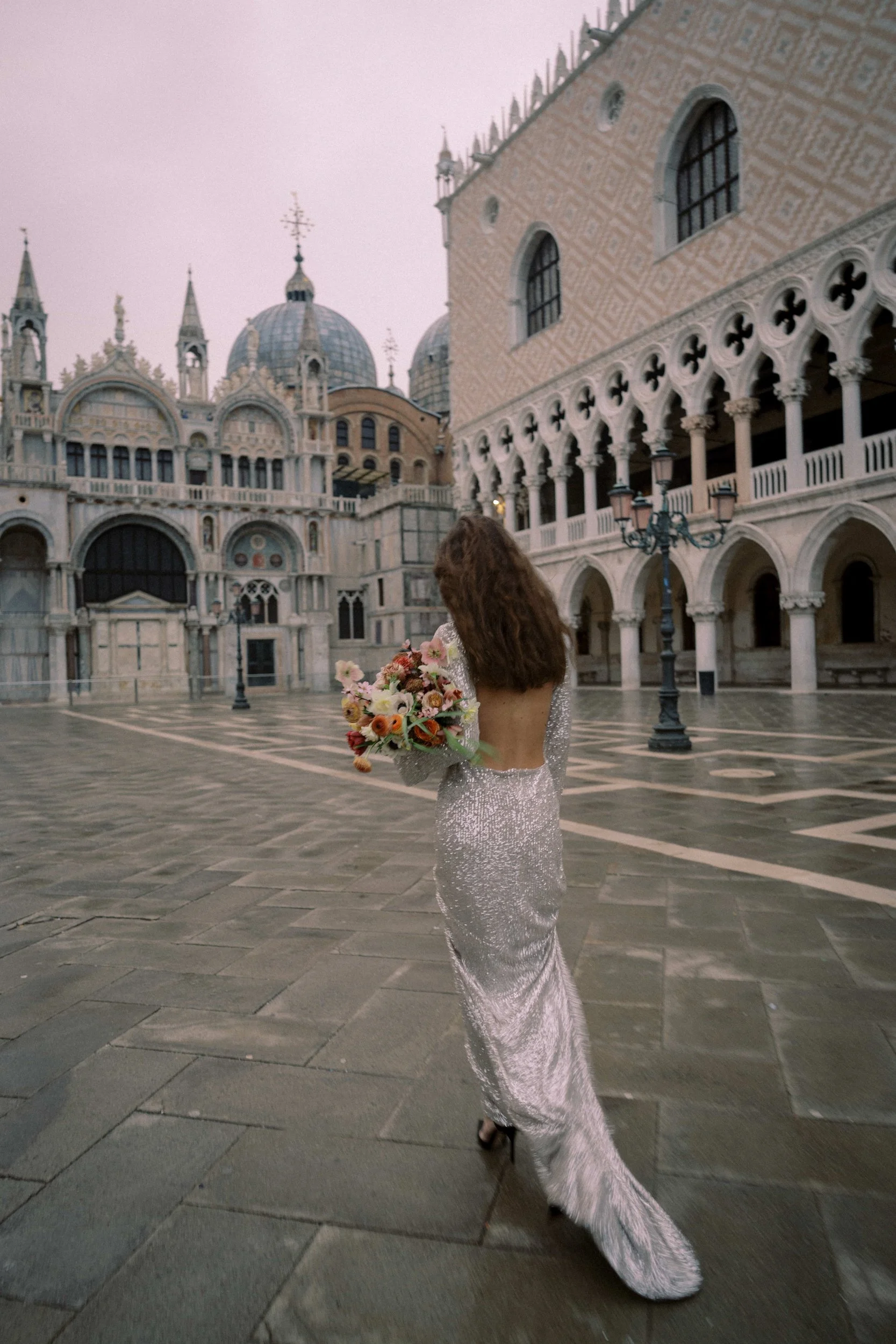 bride walking in St Mark's Square in Venice holding a bouquet of flowers