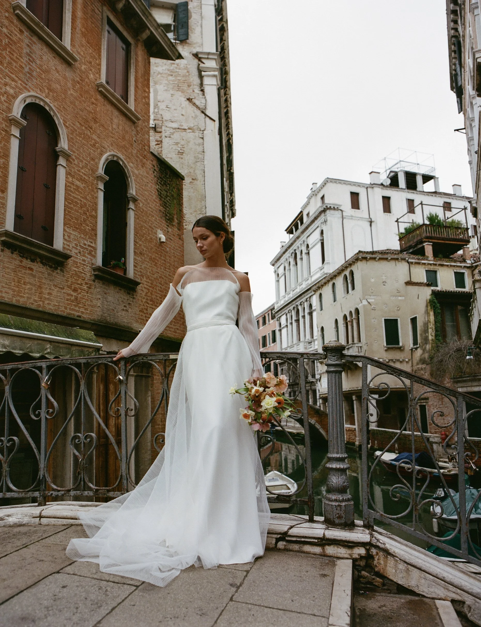 bride standing on bridge in Venice holding a bridal floral bouquet