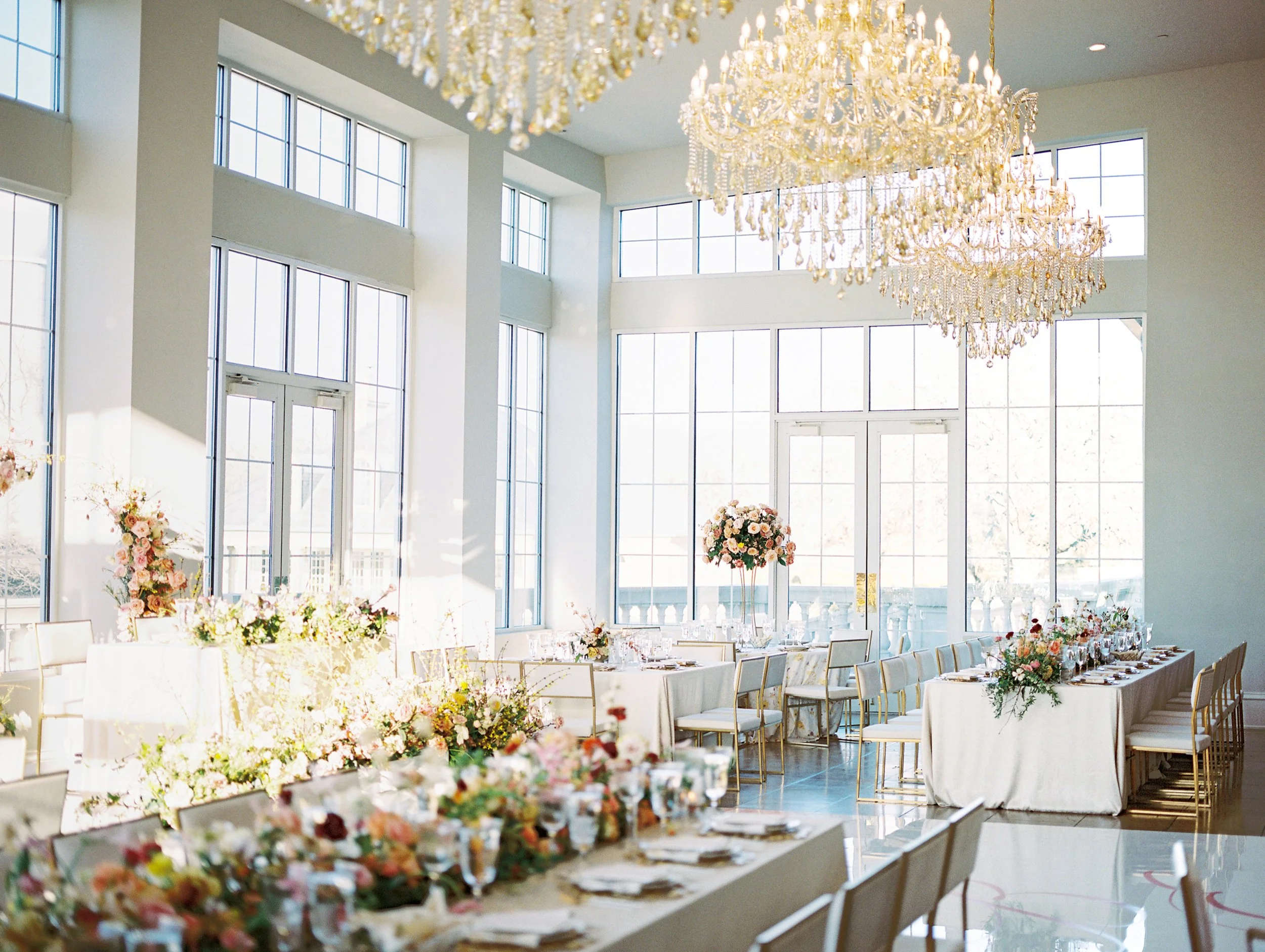a big room with chandeliers on top and long and tall flower arrangements on top