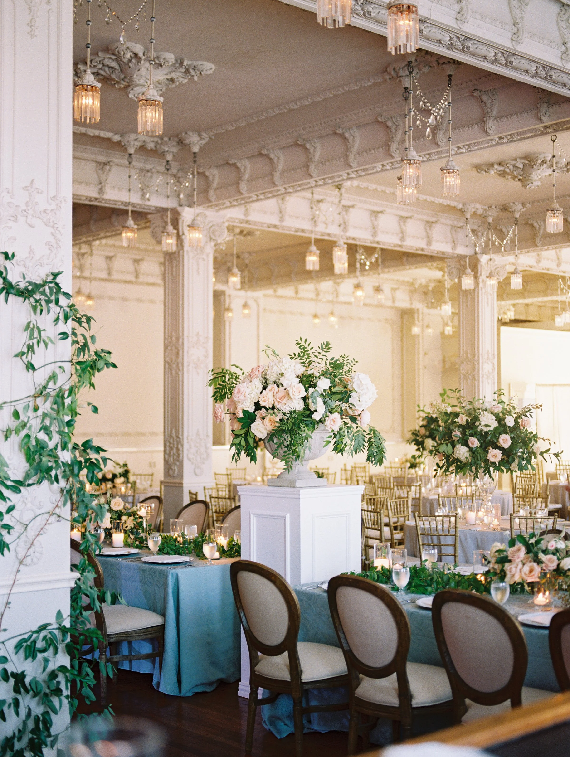 wedding reception large floral arrangement greenery pillars