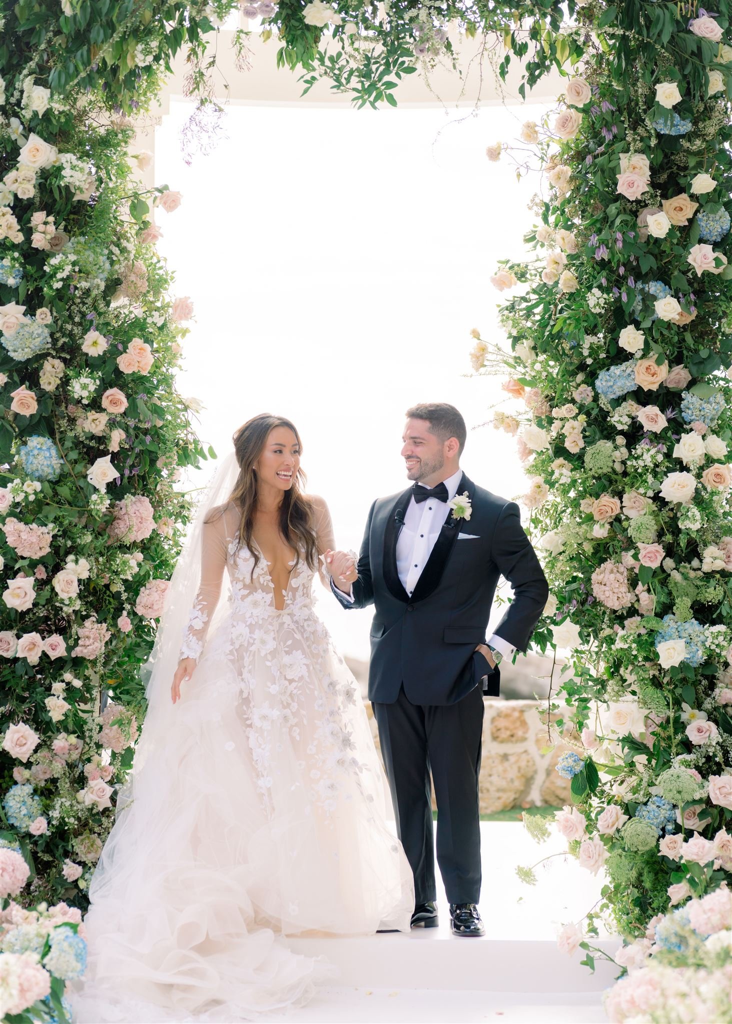 bride and groom standing in front of oversized lush floral arch at Lanikuhonua, Oahu, Hawaii