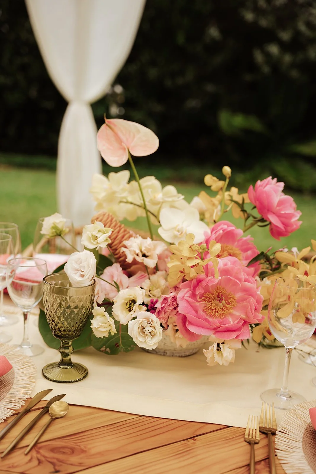 coral peonies and pink anthurium and yellow and white flowers in a bowl