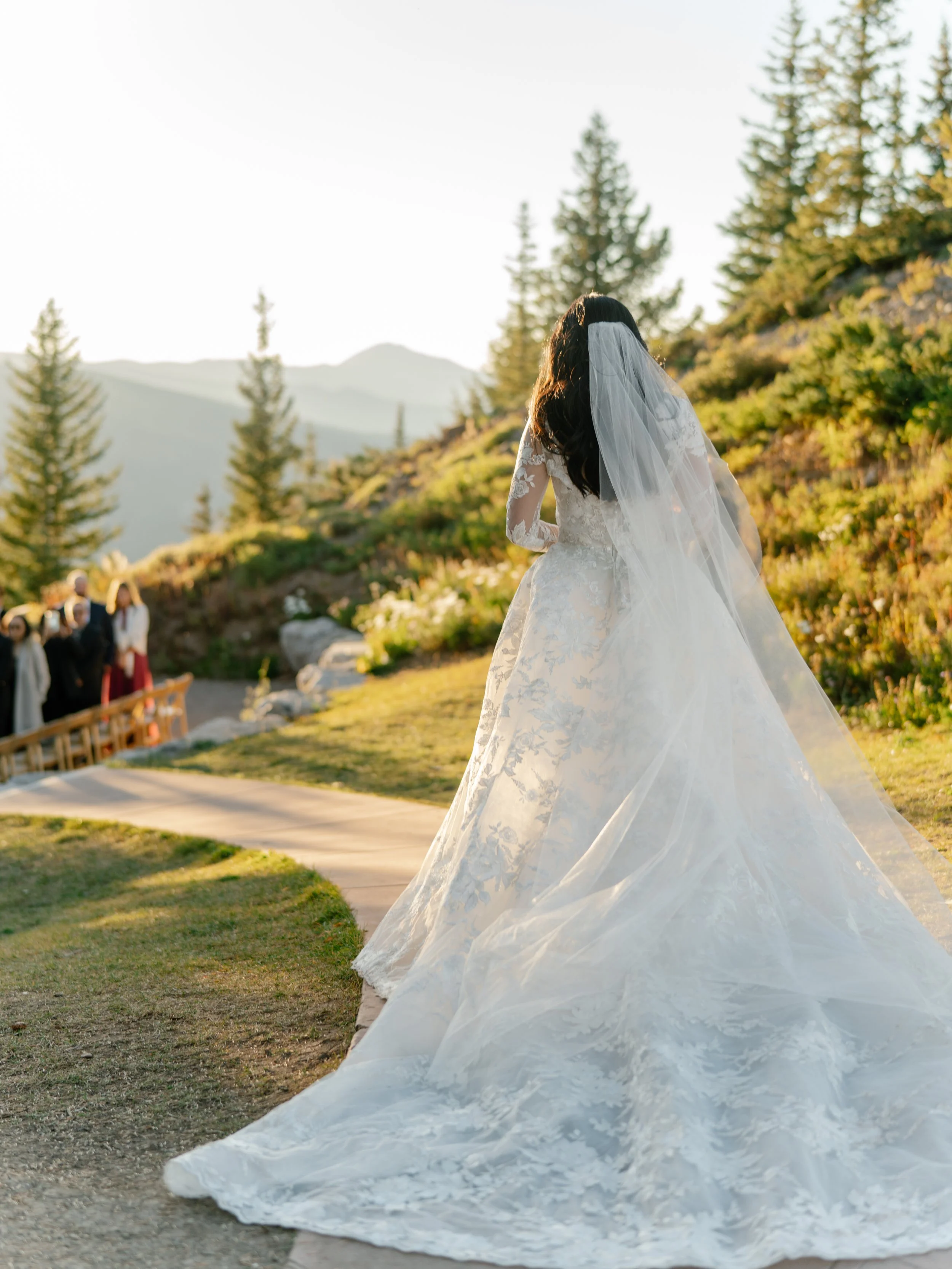 a bride in a white dress is about to walk down the aisle on top of a mountain people looking up