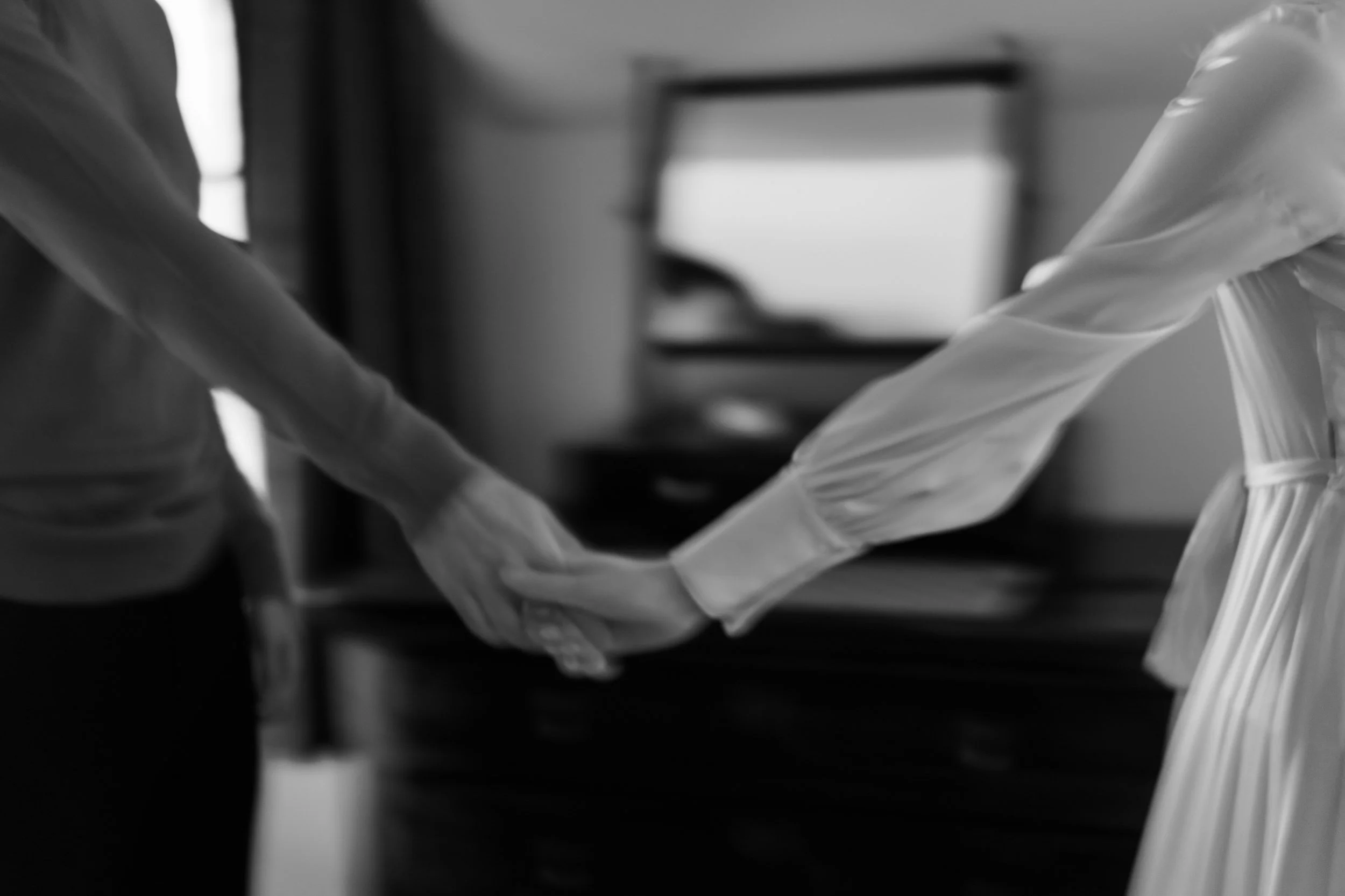 Two people holding hands, one wearing a long sleeve shirt and the other in a dress.