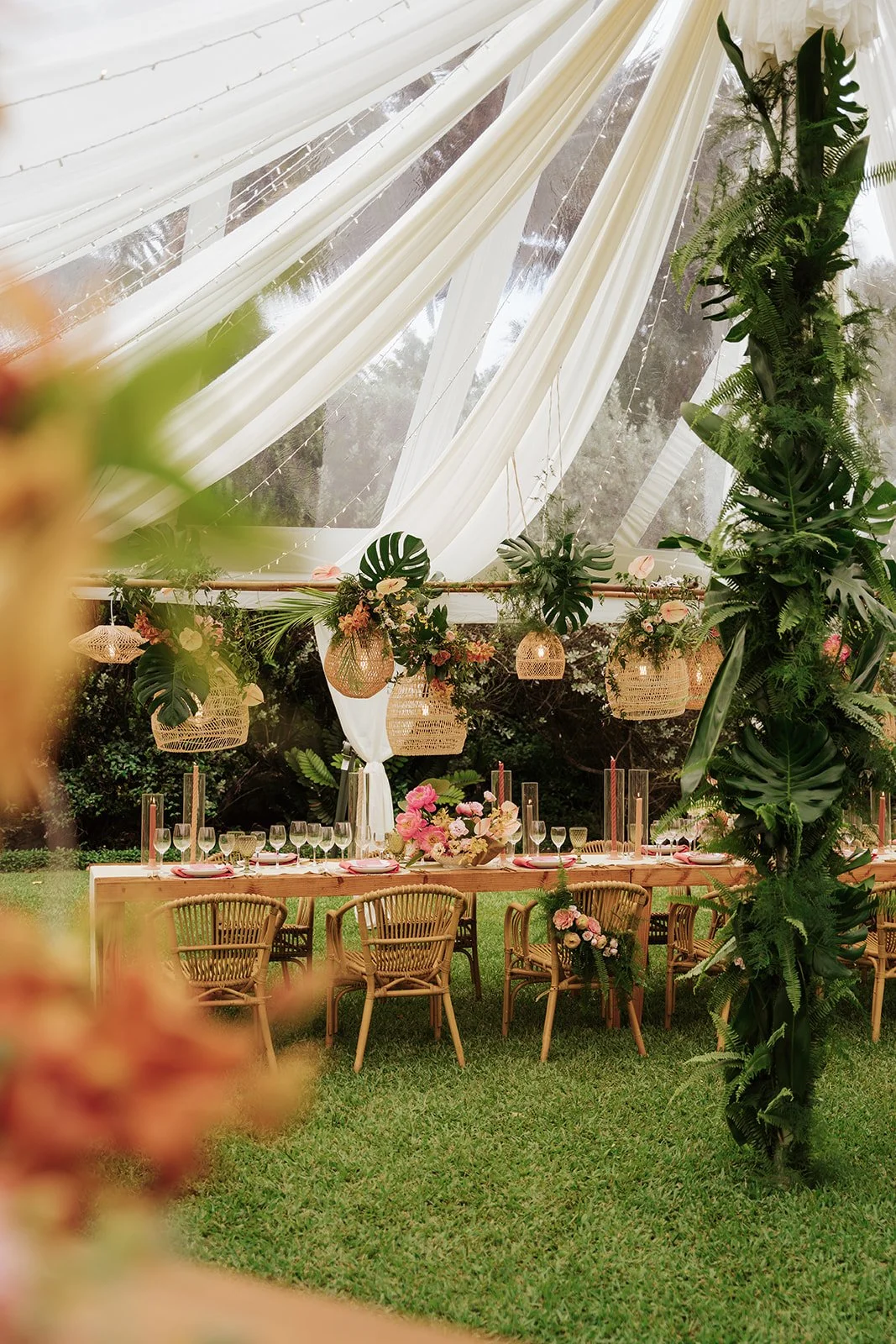 white draping with wood table and chairs underneath and greenery