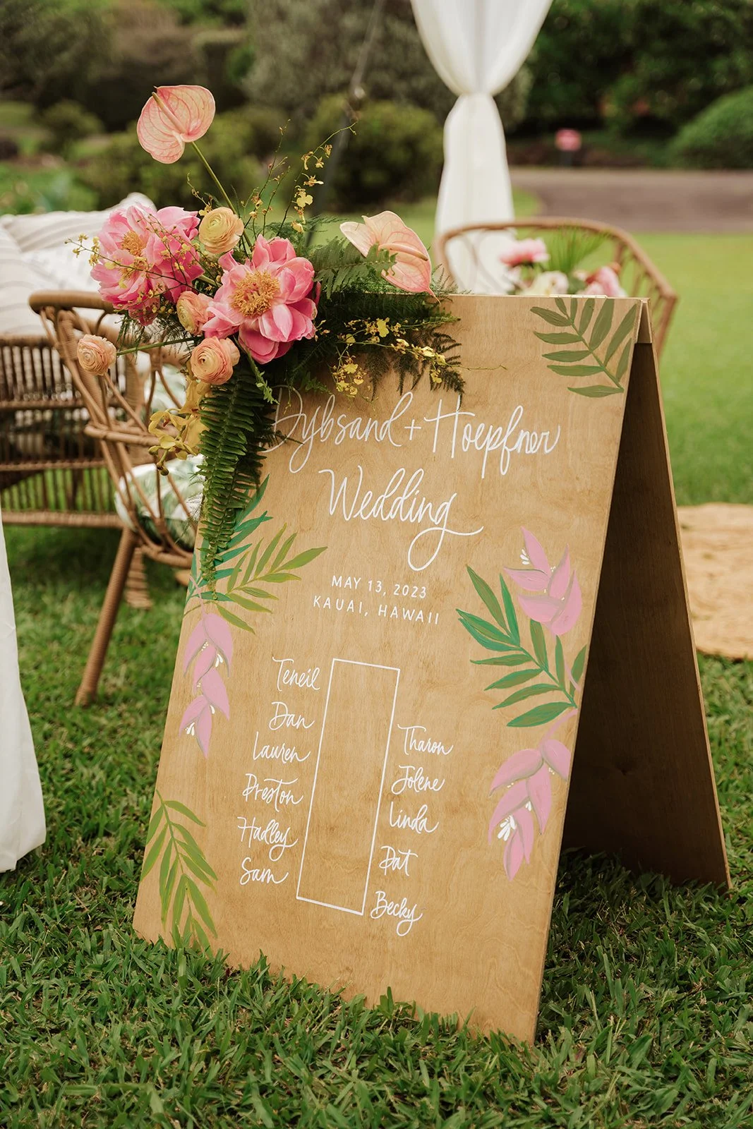pink peonies and tropical leaves on corner of wooden sign with people's name on it