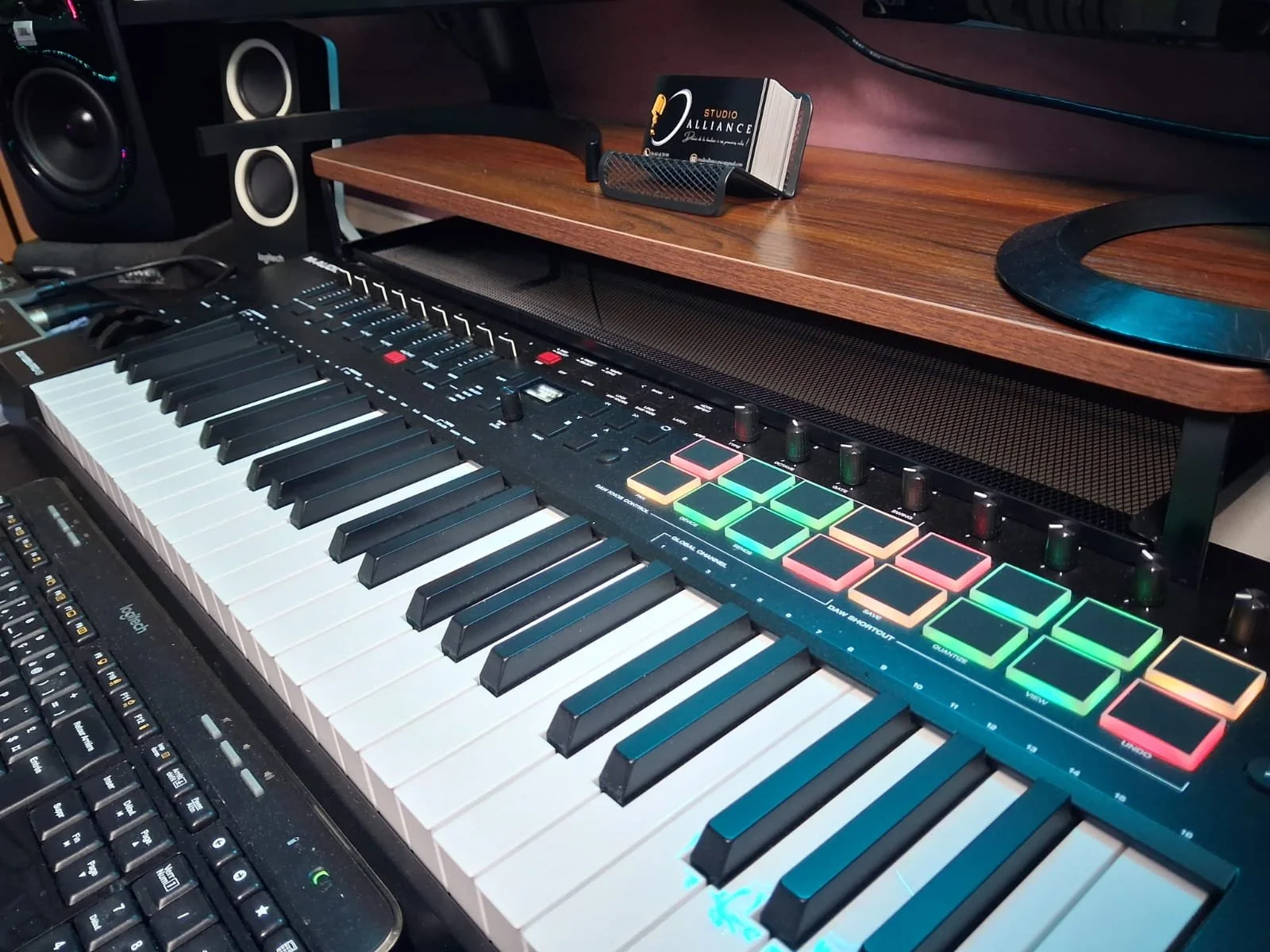 Clavier MIDI avec pads lumineux dans un studio d'enregistrement, avec enceintes et ordinateur.