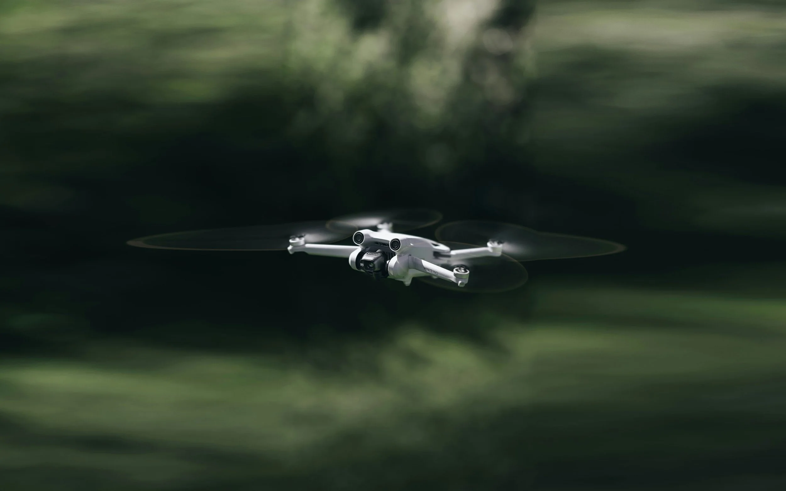 Drone blanc volant dans un environnement verdoyant, flou d'arrière-plan.