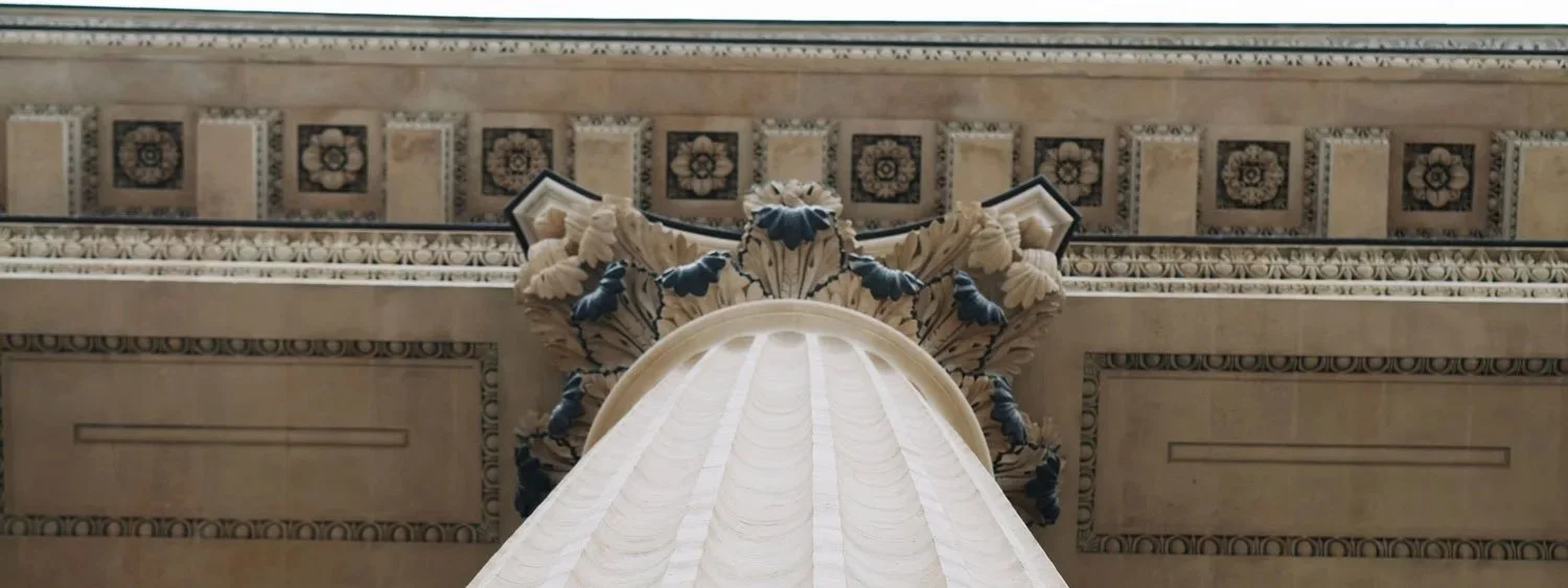 Vue en contre-plongée d'une façade décorative architecturale avec des éléments sculptés en pierre, modèle classique, probablement dans un bâtiment historique.