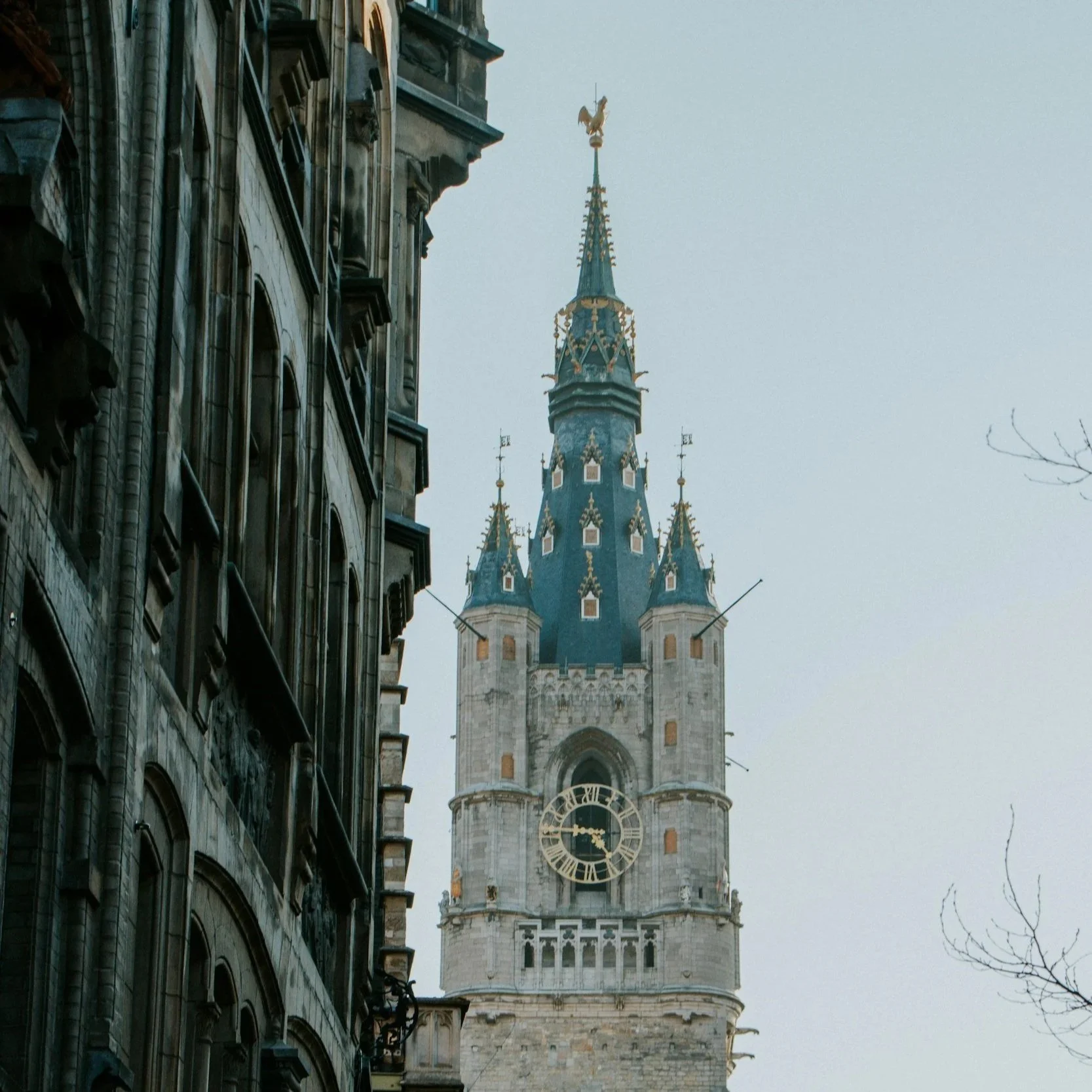Une tour de château avec un cadran d'horloge doré sur fond de ciel clair.