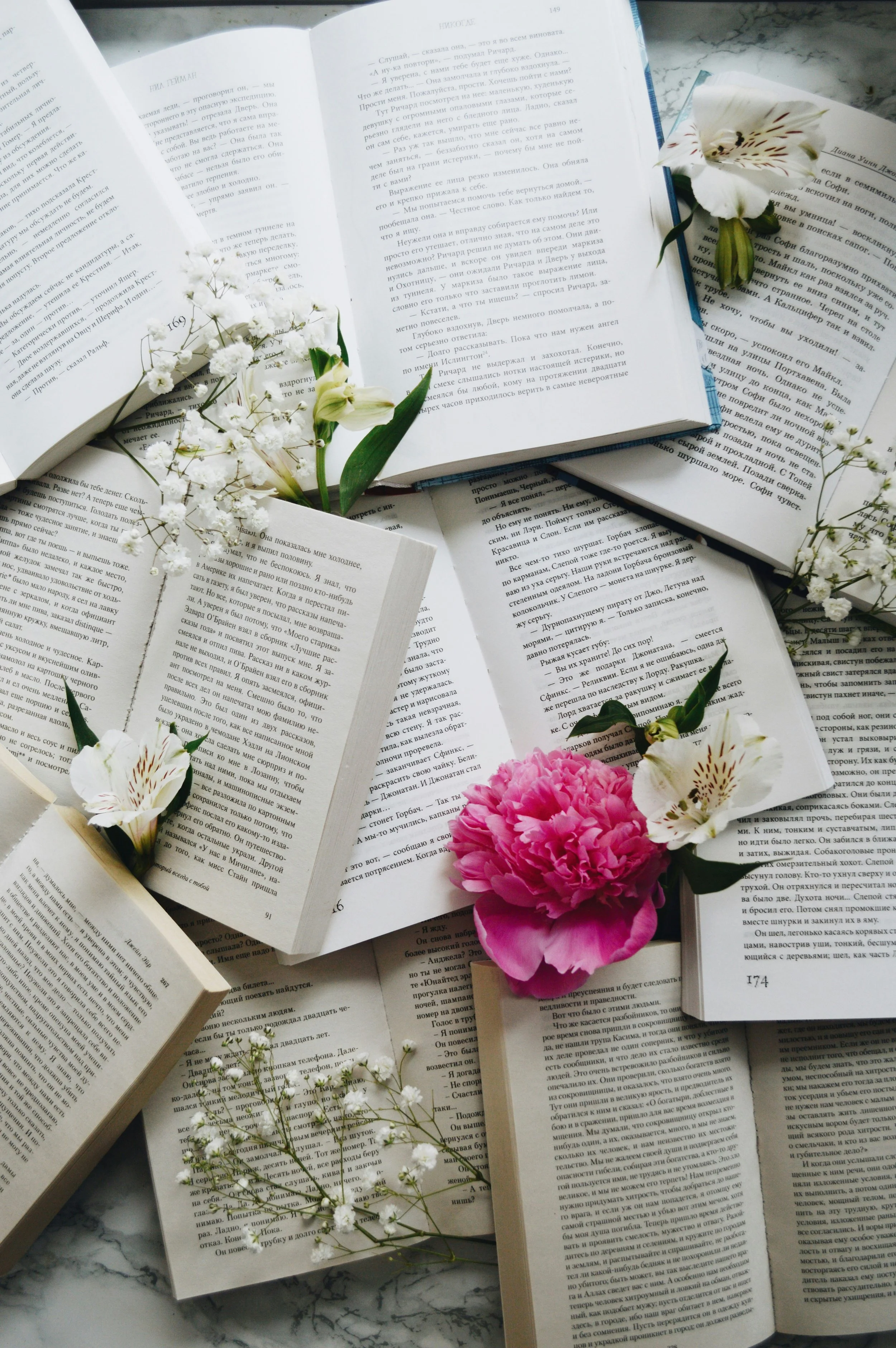 Viele offene Bücher mit weißen und rosa Blumen, darunter Graublatt