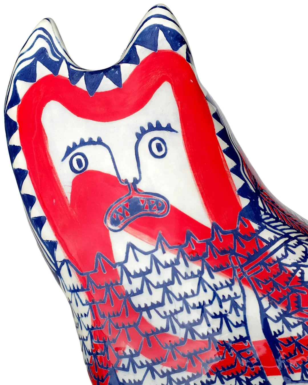 Decorative ceramic cat close up with red, white, and blue colours, featuring a face with expressive eyes, a nose, and a mouth.