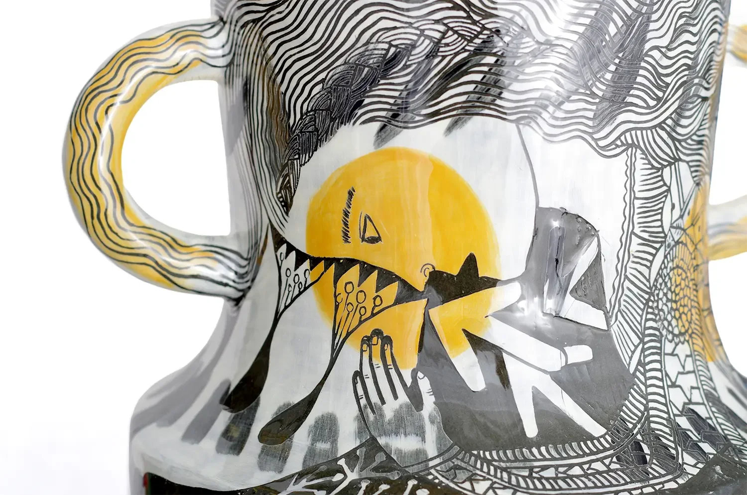 Decorative ceramic vase close up with black and yellow abstract illustrations, featuring a yellow circle, black spiked shapes, and hand drawings.