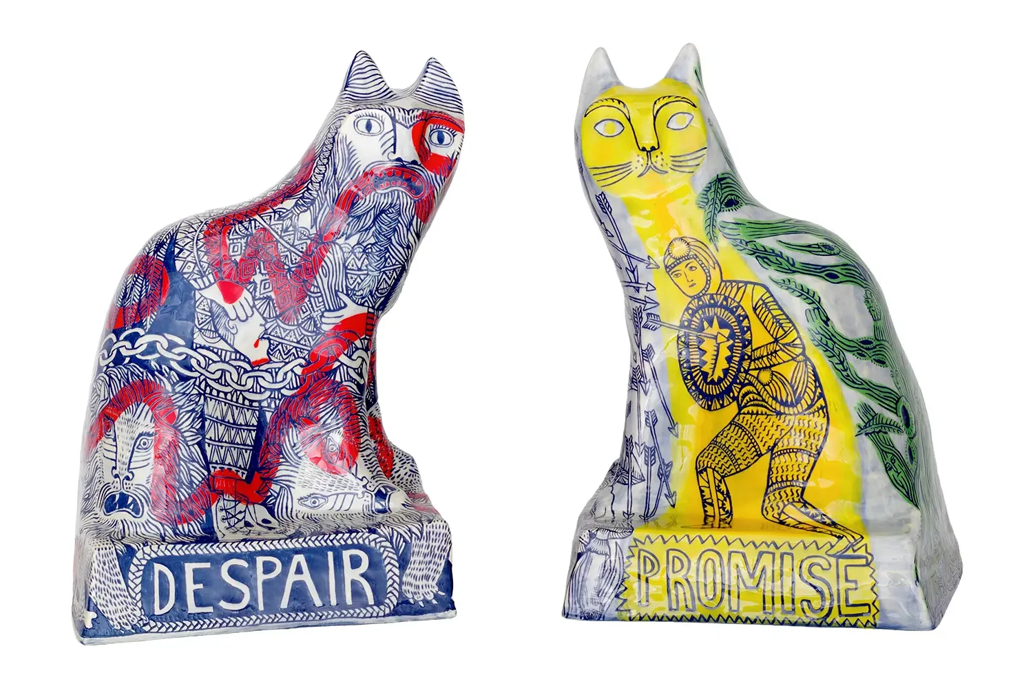 Two ceramic cat sculptures with intricate illustrations and text. The sculpture on the left features the word 'DESPAIR' and depicts a  figure with various detailed patterns. The sculpture on the right features the word 'PROMISE'.