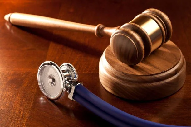 Gavel and stethoscope on a wooden surface.