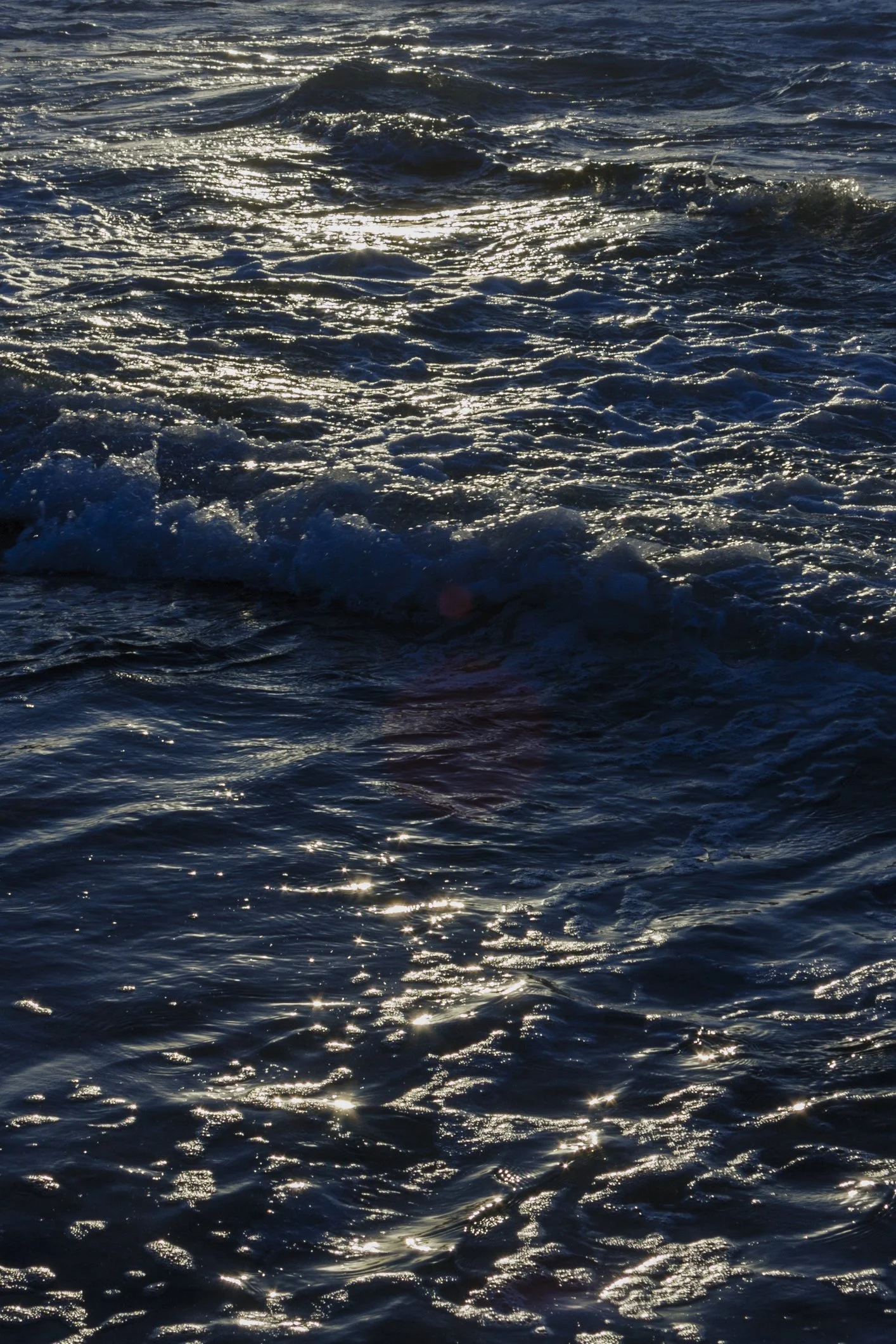 Ozeanwellen bei Sonnenuntergang, reflektierendes Licht auf der Wasseroberfläche.