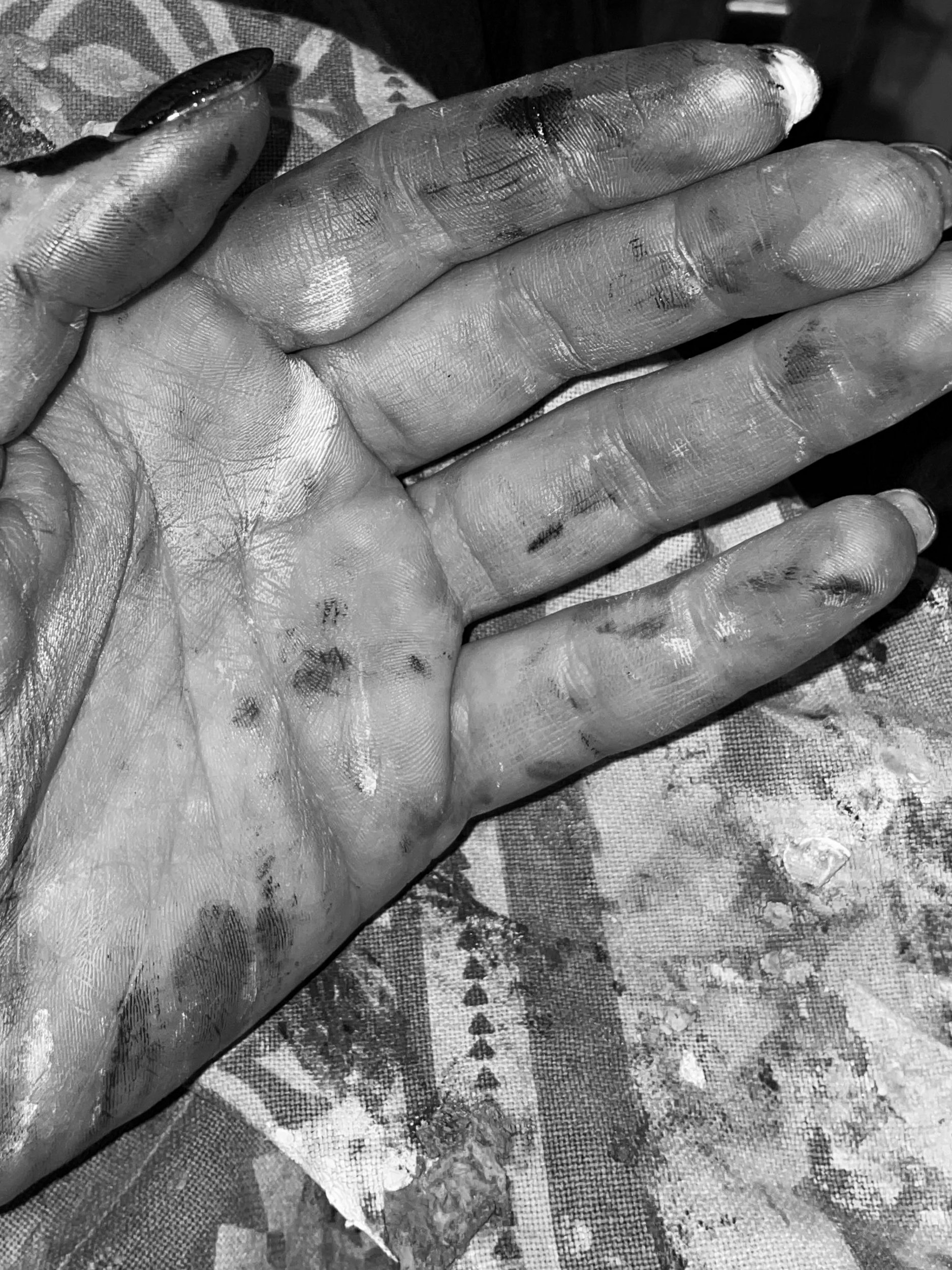 Main saleuse et sale avec de la peinture, posé sur un tissu teint avec des motifs.