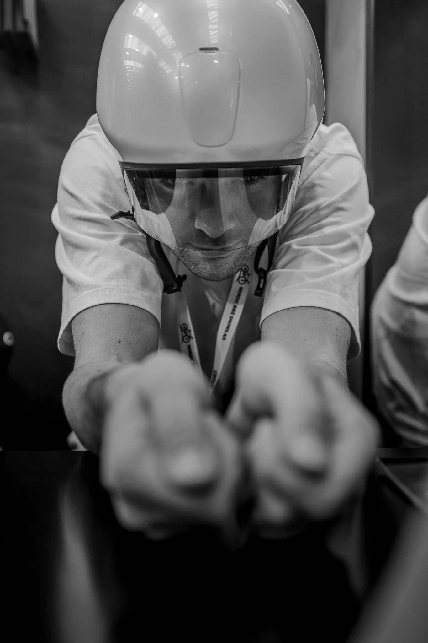 Person wearing a helmet and aiming forward with both hands, in black and white.