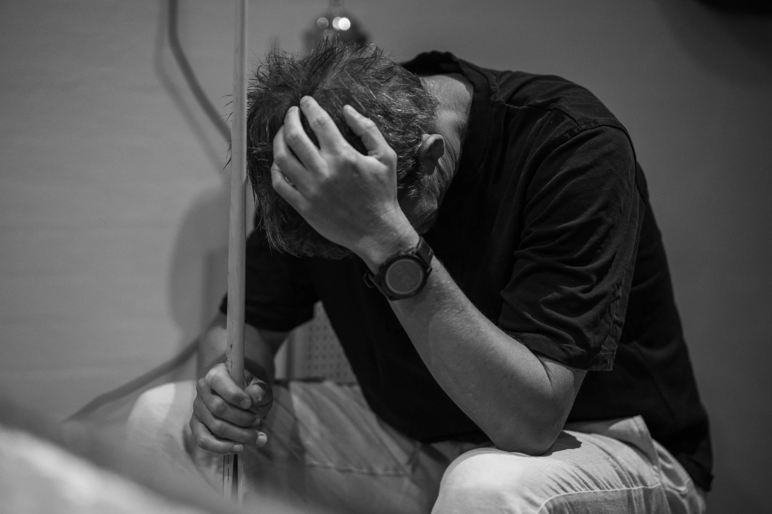 Black and white portrait capturing a quiet, introspective moment, showing a man resting with his head in his hand, conveying emotion, vulnerability, and human reflection.