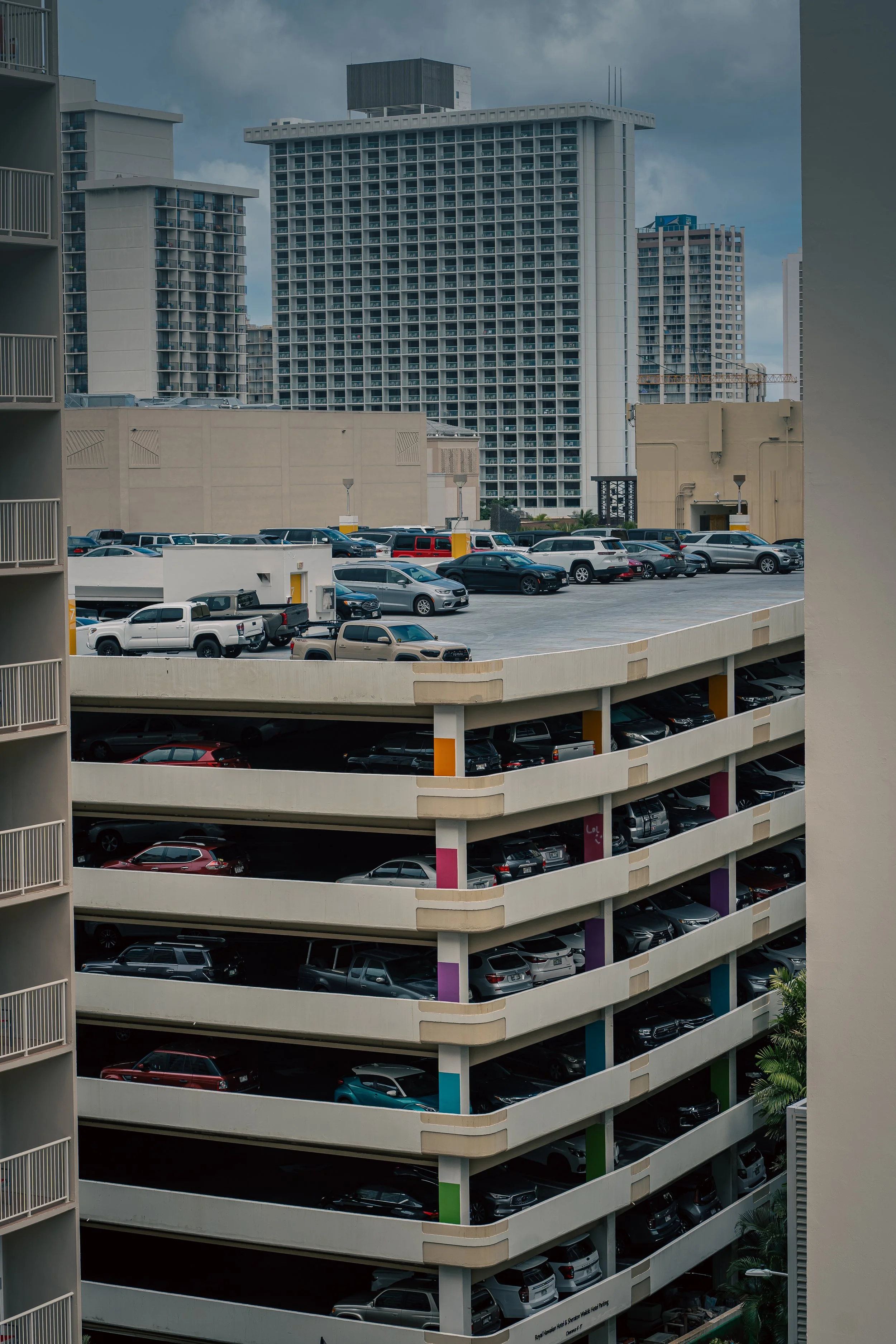 Urban cityscape featuring a multi-level parking garage framed by high-rise buildings, capturing modern architecture, density, and everyday metropolitan life.