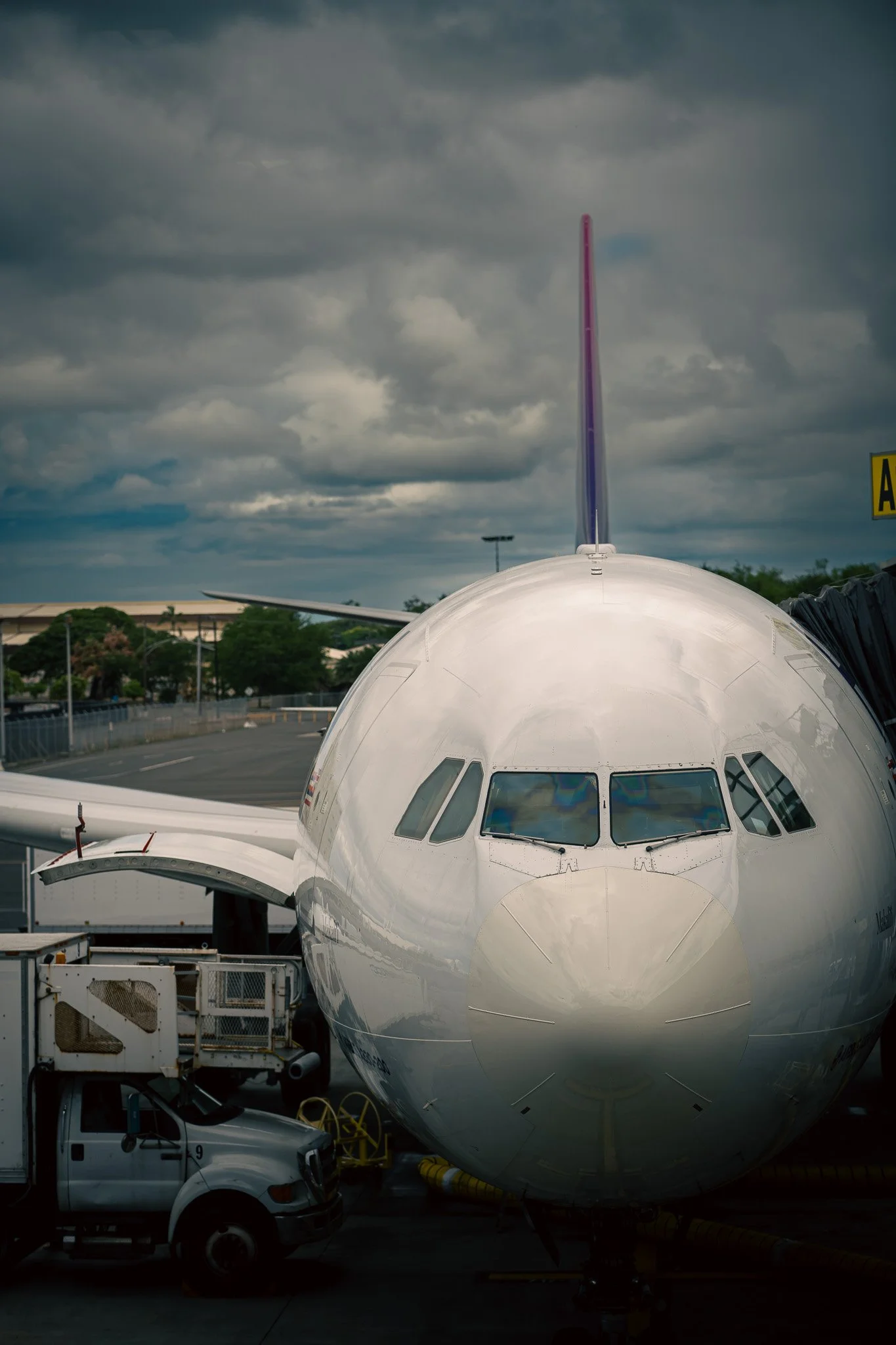 Front view of a commercial airplane parked at an airport gate under a cloudy sky.