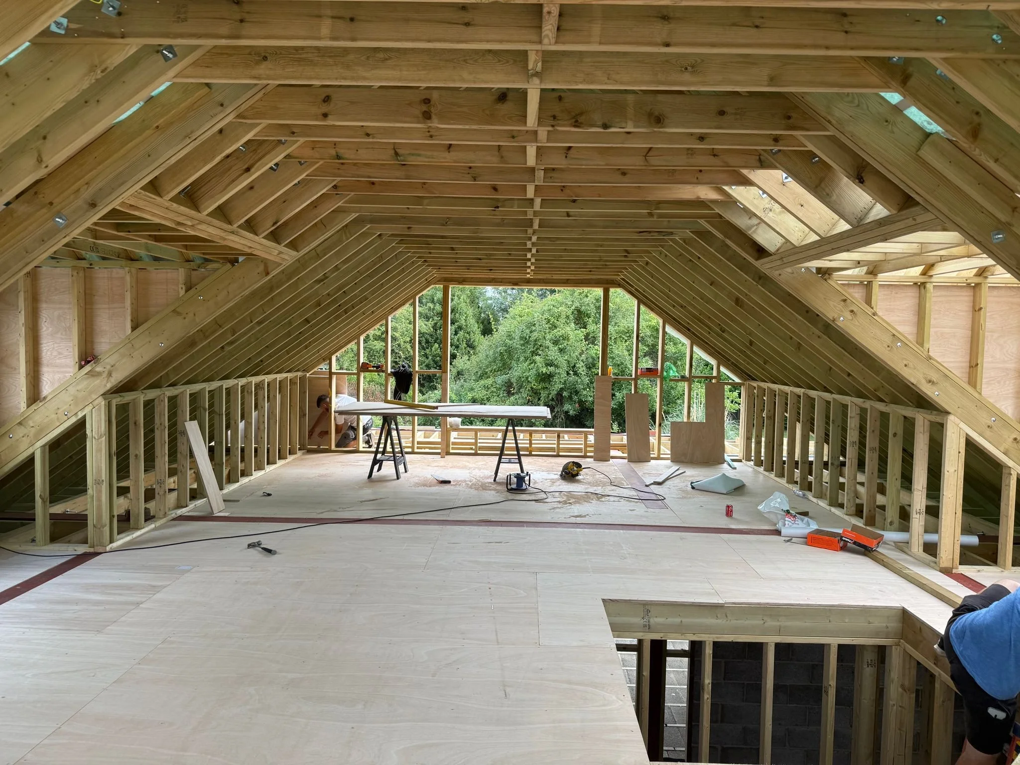 Interior of an attic under construction with wooden framing, plywood flooring. Carpentry and Renovation by DA Build in London, Surrey and Greater London.