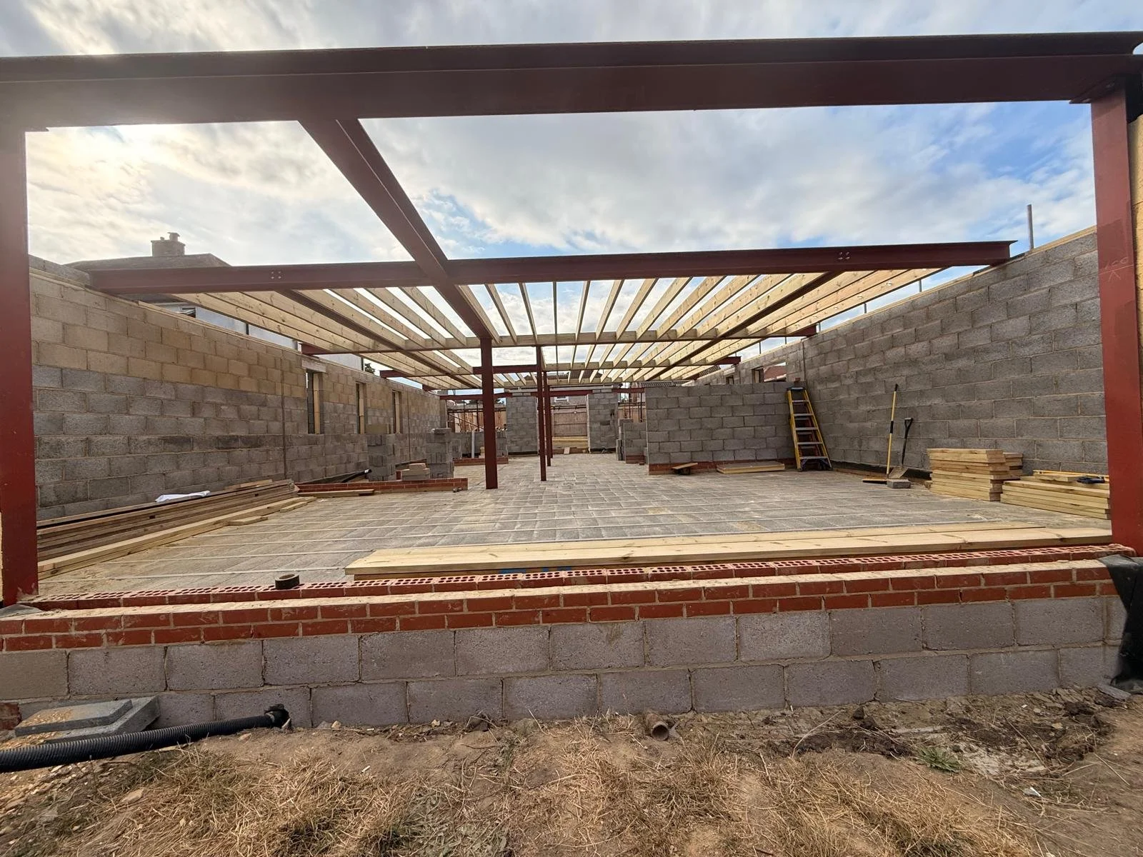 Construction site with brick and cinder block walls, wooden beams, and a paved flooring.  Carpentry, construction and Renovation by DA Build in London, Surrey and Greater London.