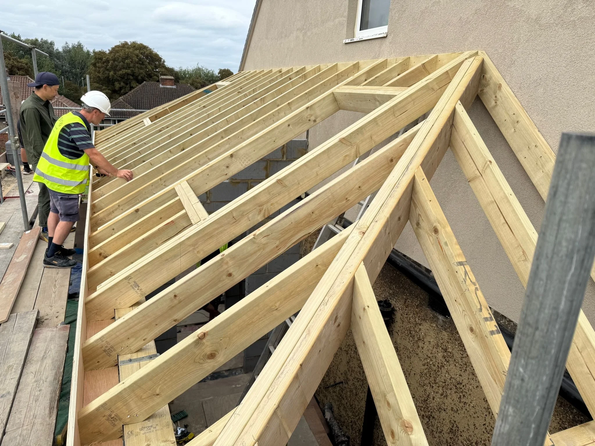 Construction workers installing the new wooden roof framework on a building.  Carpentry, construction and Renovation by DA Build in London, Surrey and Greater London.