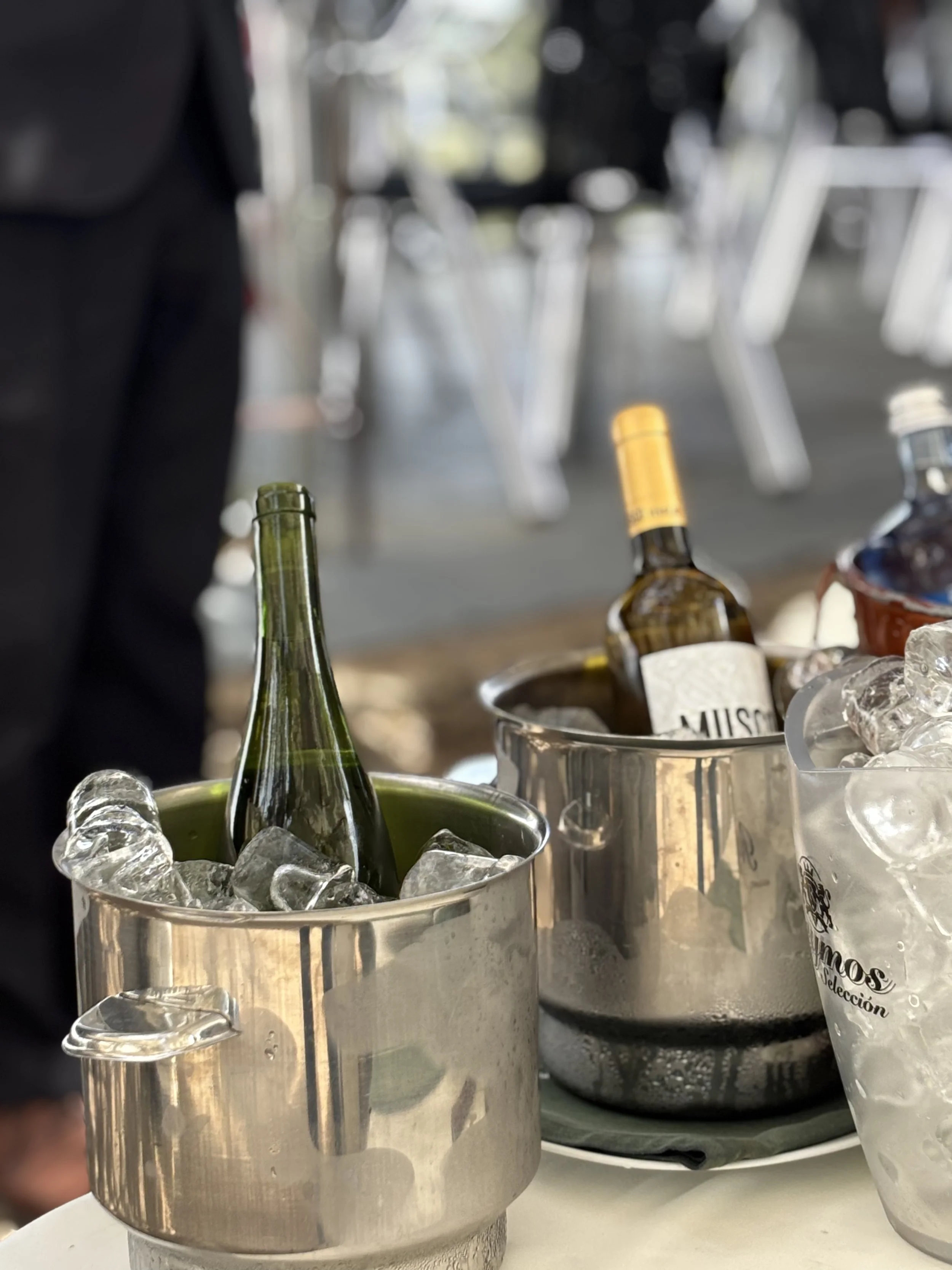 Vasos de metal con hielo y botellas de vino o alcohol en un evento social.