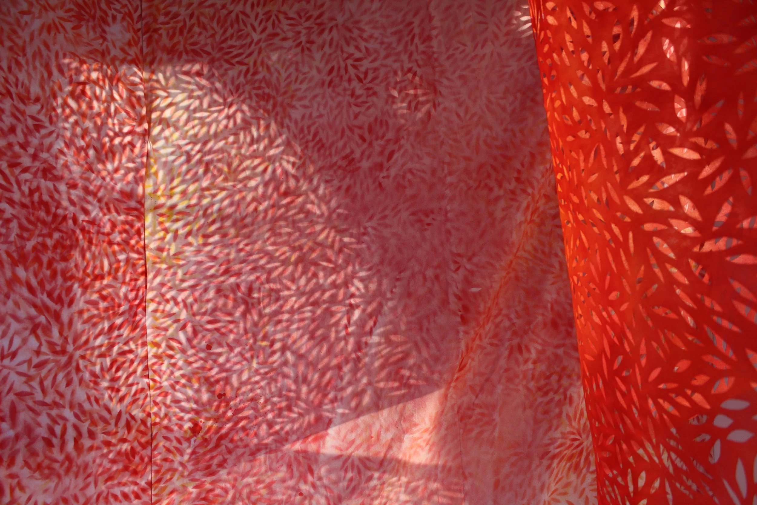 Colorful fabric with intricate cut-out patterns creating shadows on the surface.