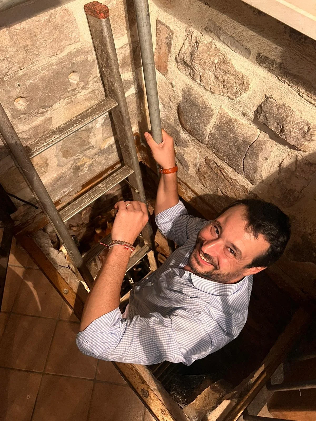 Uomo che lavora su una scala di metallo in un ambiente con pareti di pietra