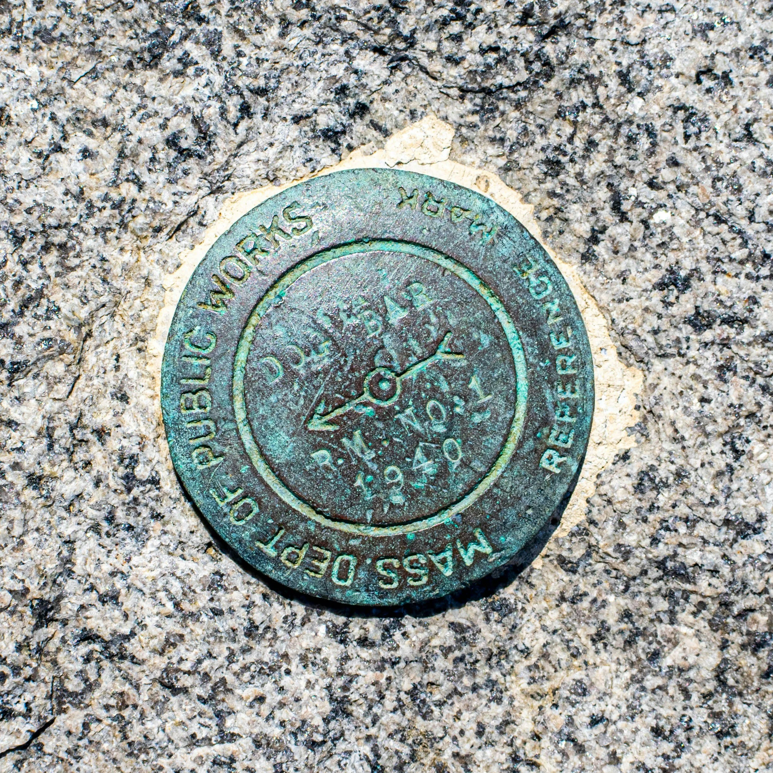 A circular metal plaque embedded in concrete, indicating the opening of the Department of Public Works wastewater release in 1940.