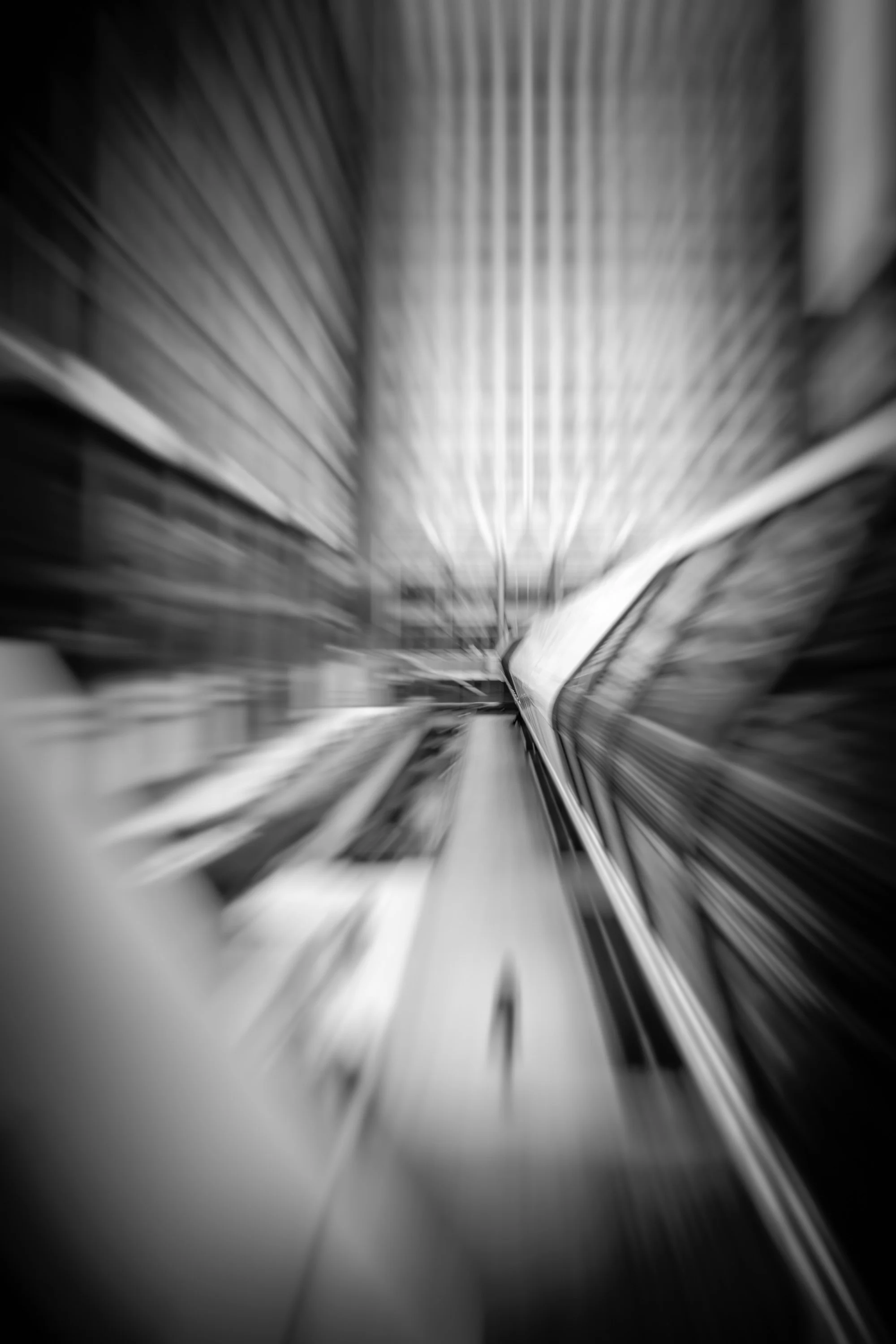 Abstract black-and-white view of modern architecture in Canary Wharf, with motion blur and converging structural lines.
