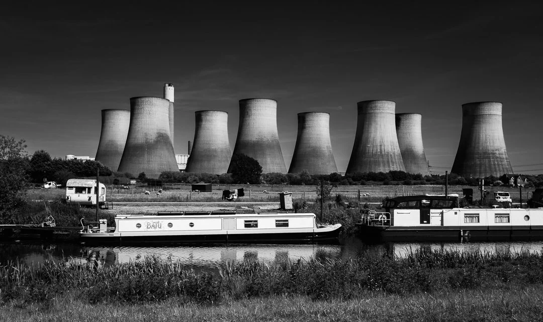 Narrowboats moored along a canal with the eight cooling towers of Ratcliffe-on-Soar Power Station dominating the distant landscape.