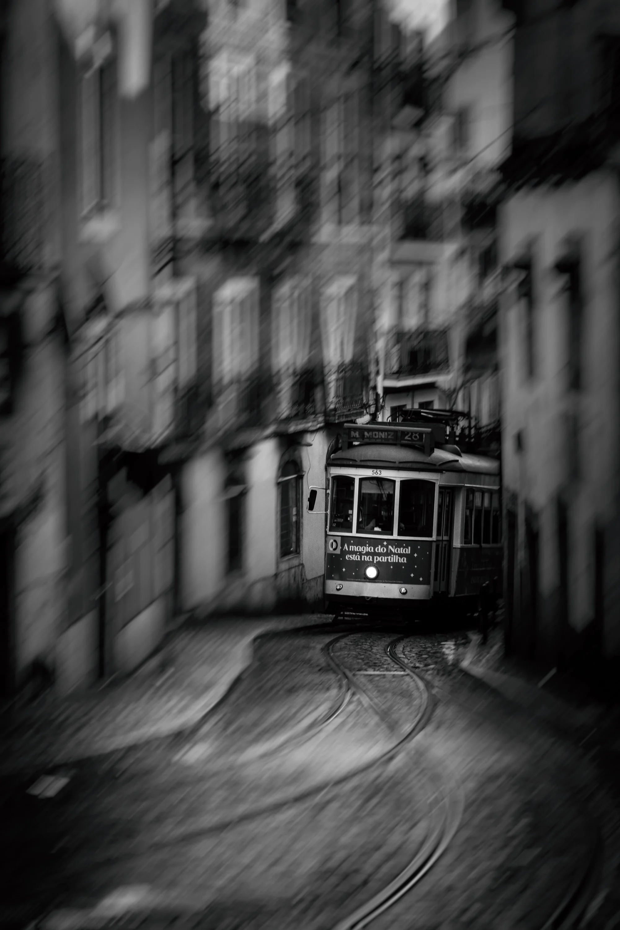 Tram travelling along a narrow Lisbon street, framed by the buildings lining either side.
