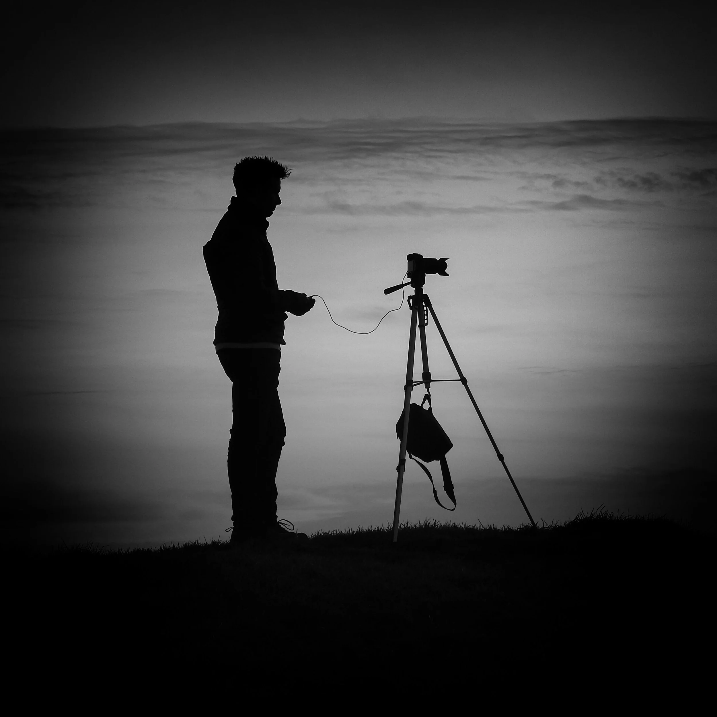 Ben Speed silhouetted beside a tripod in the South Downs National Park beneath a cloudy sky.