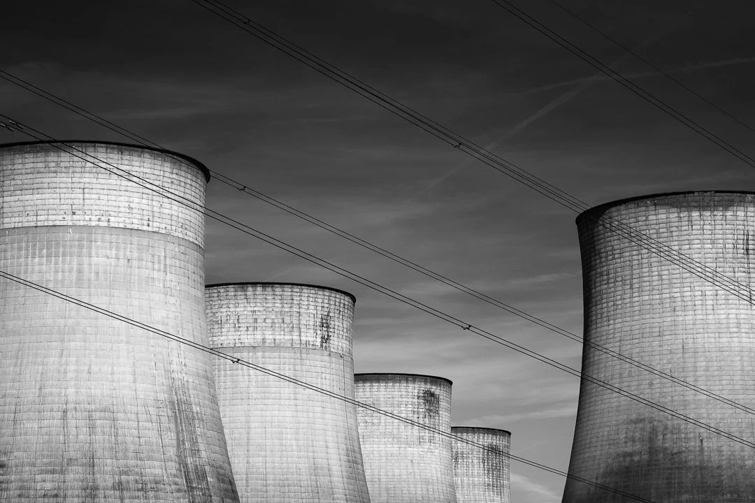 Electricity cables crossing diagonally in front of the cooling towers at Ratcliffe-on-Soar Power Station, photographed in monochrome.