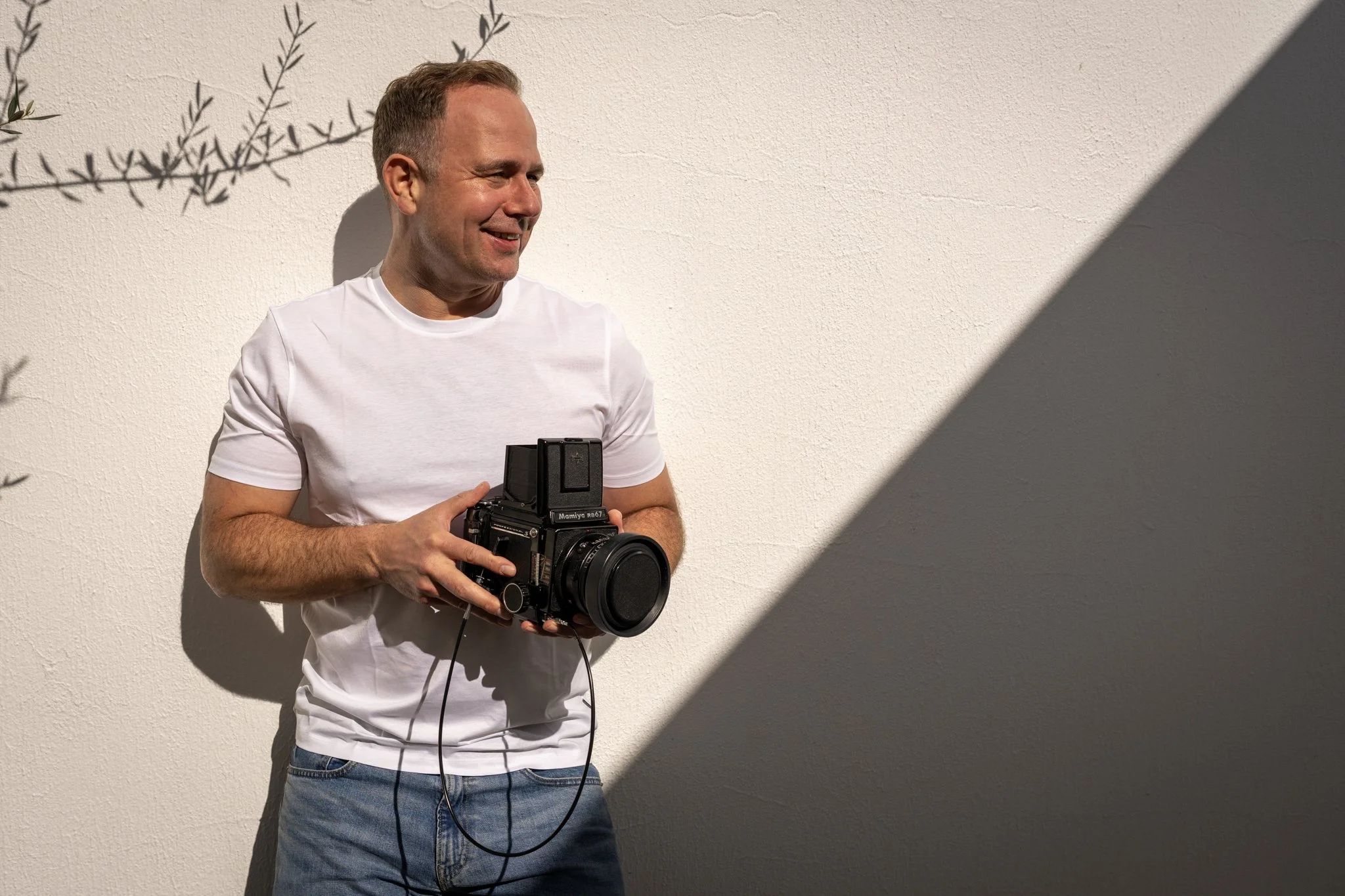 Holger Pfeiffer smiling with a camera