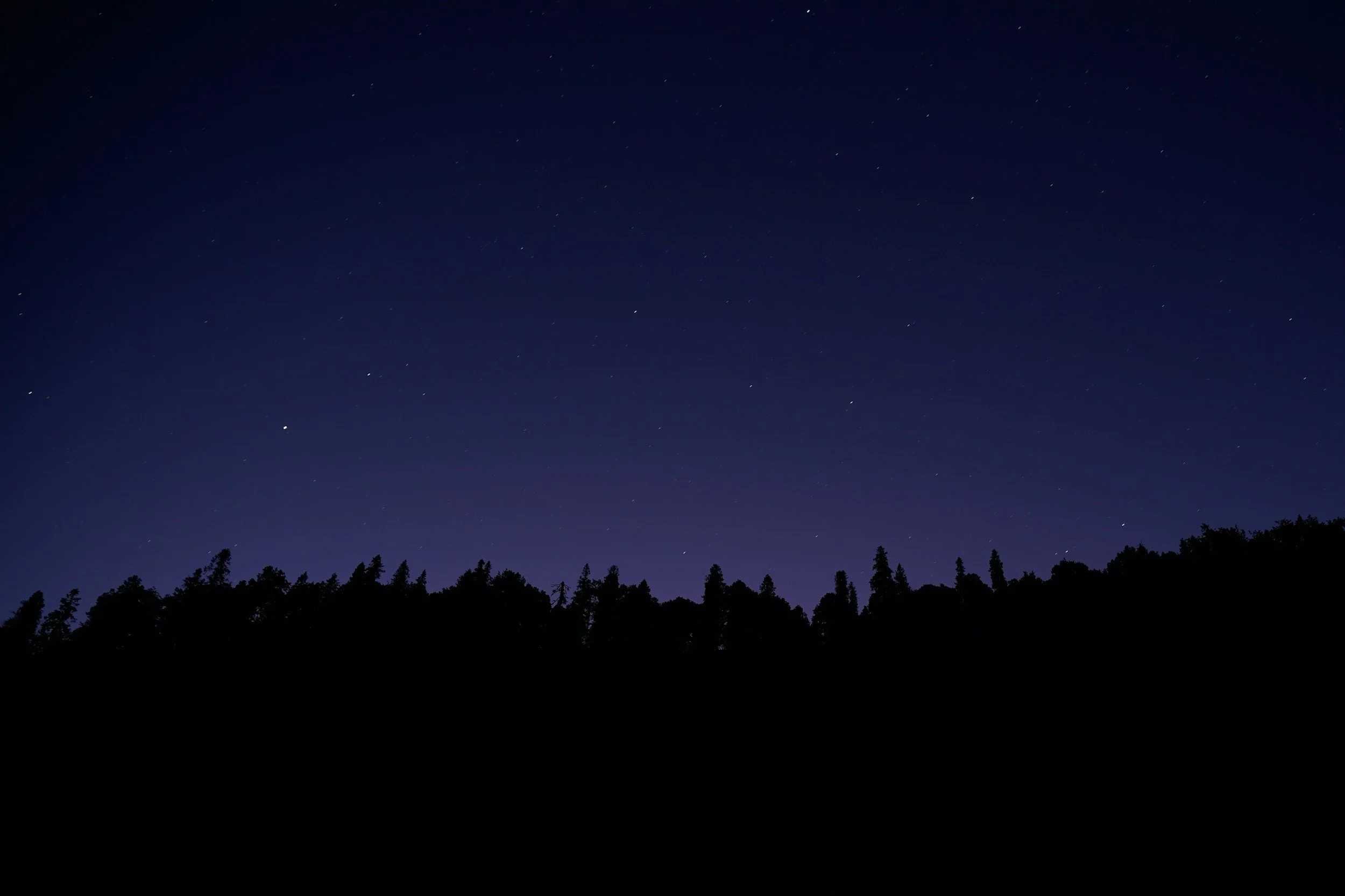 A doctor and a patient are sitting at a desk in a medical office. The doctor is smiling and holding a clipboard, while the patient is reaching out to shake hands. Both are smiling and making eye contact.