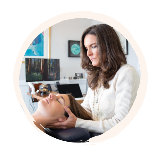 Woman receiving a facial massage from a cosmetologist or aesthetician in a professional treatment room.