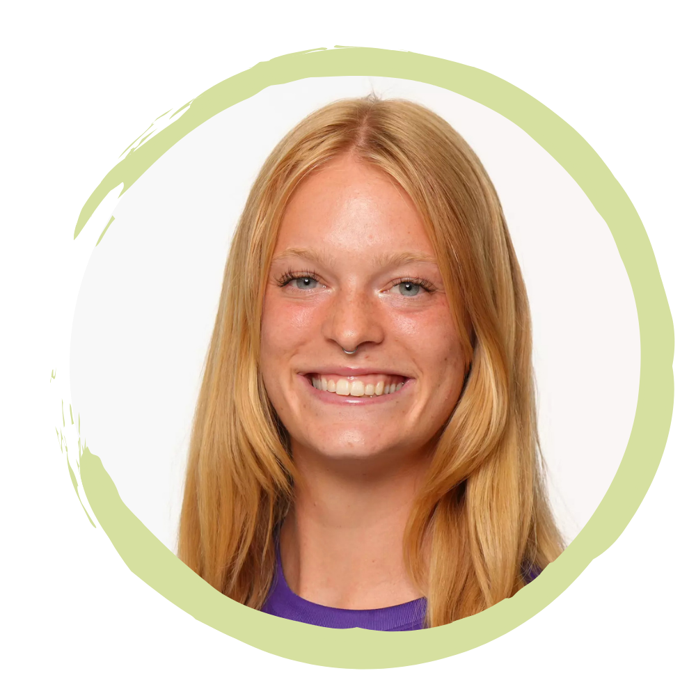 Close-up portrait of a young woman with long red hair, blue eyes, and a bright smile, against a white background with a green border.