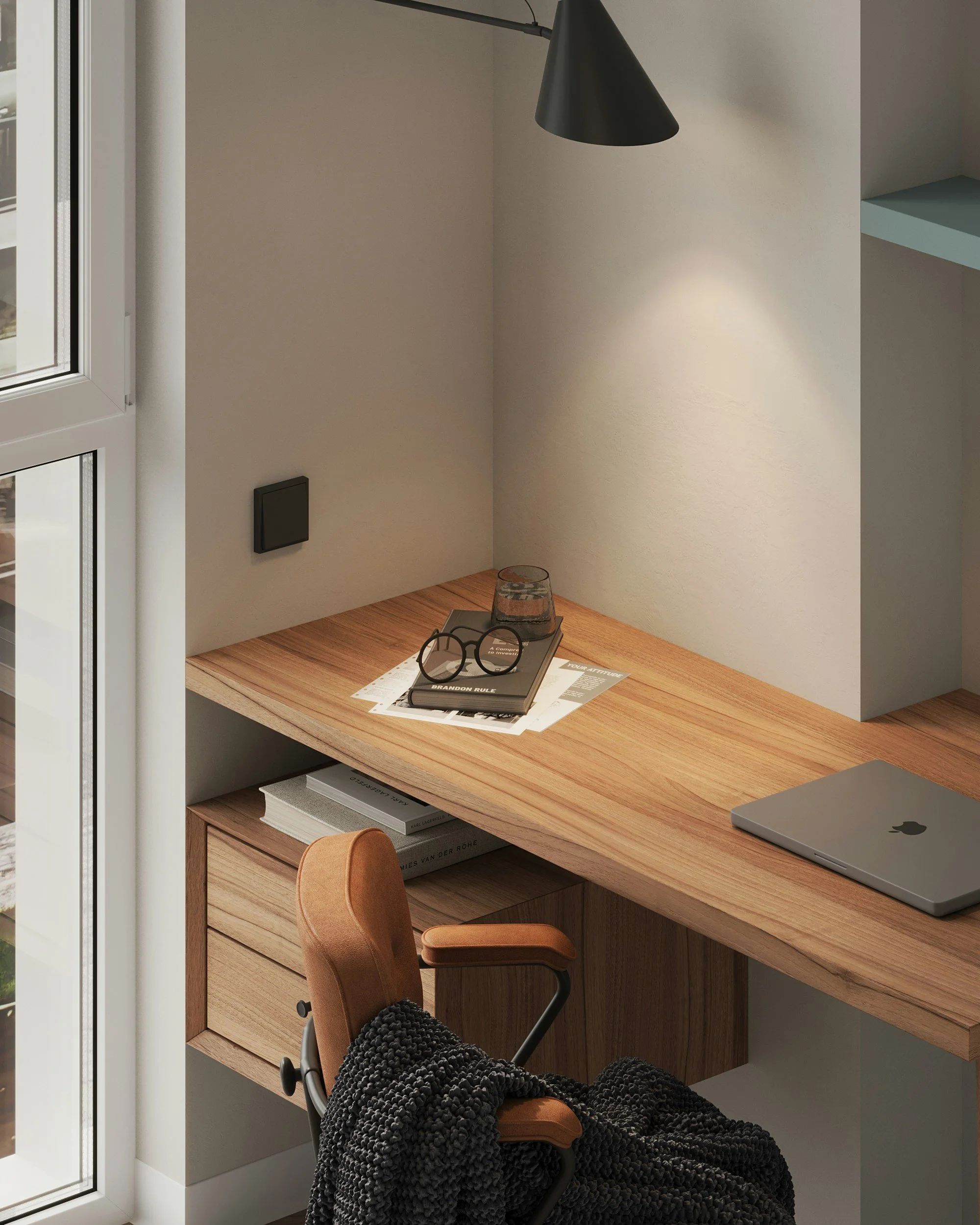 A minimalistic wooden desk in a home office near a window, with a laptop, glasses, a glass of water, and some papers on it.