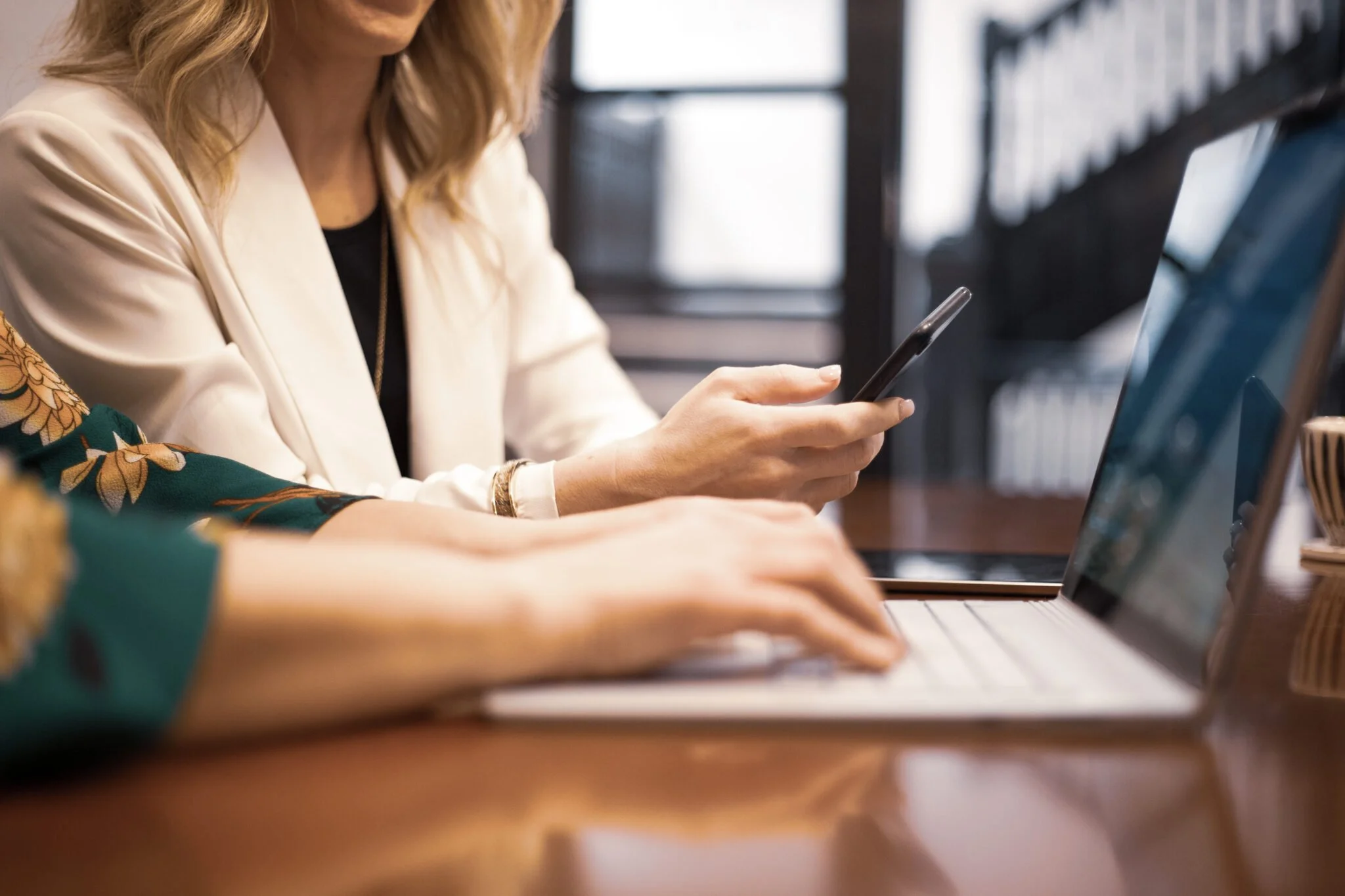 Two people working together on phone and laptop.
